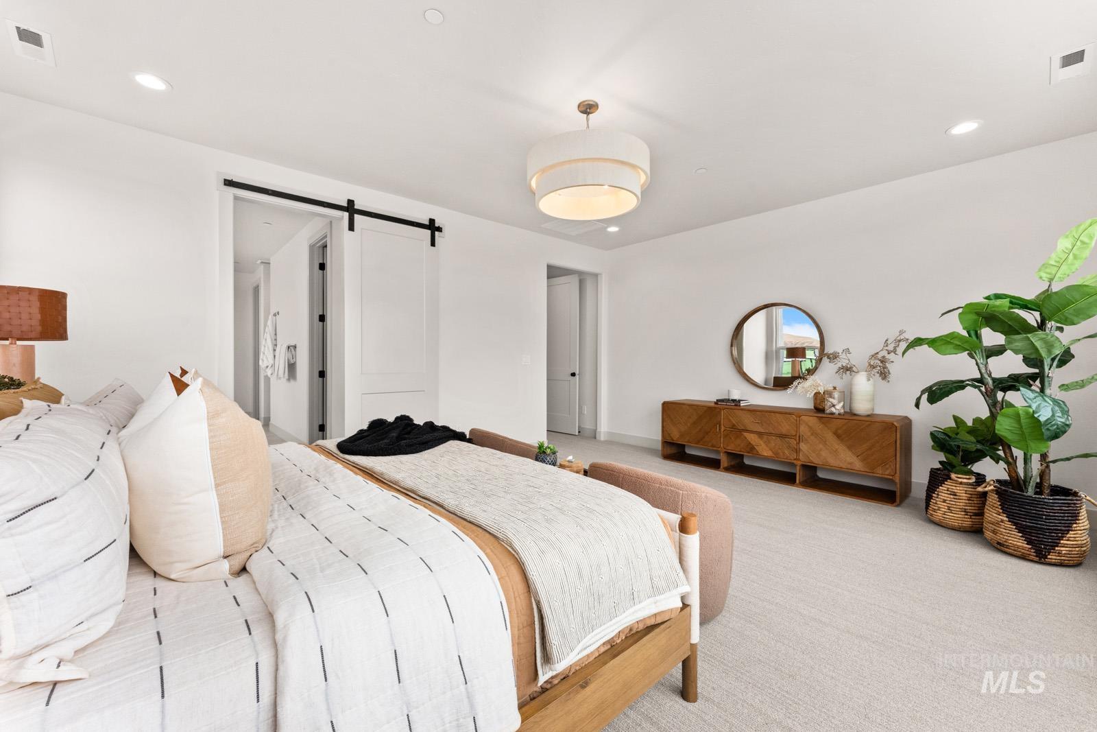 Carpeted bedroom featuring a barn door, recessed lighting, and connected bathroom