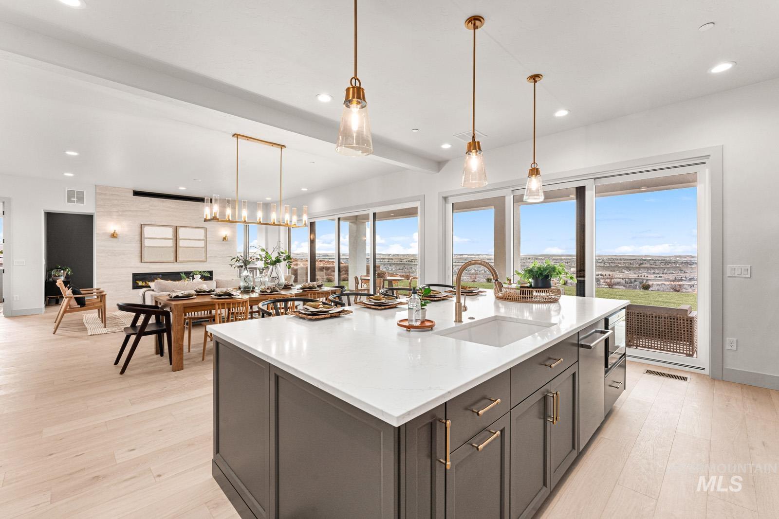 Kitchen with decorative light fixtures, light stone counters, and light wood-style flooring