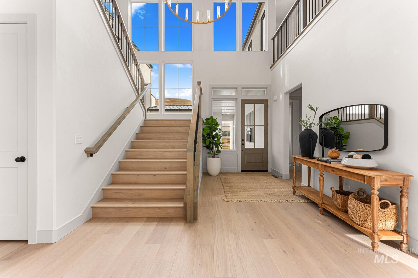Foyer entrance with light wood finished floors, a high ceiling, and a chandelier
