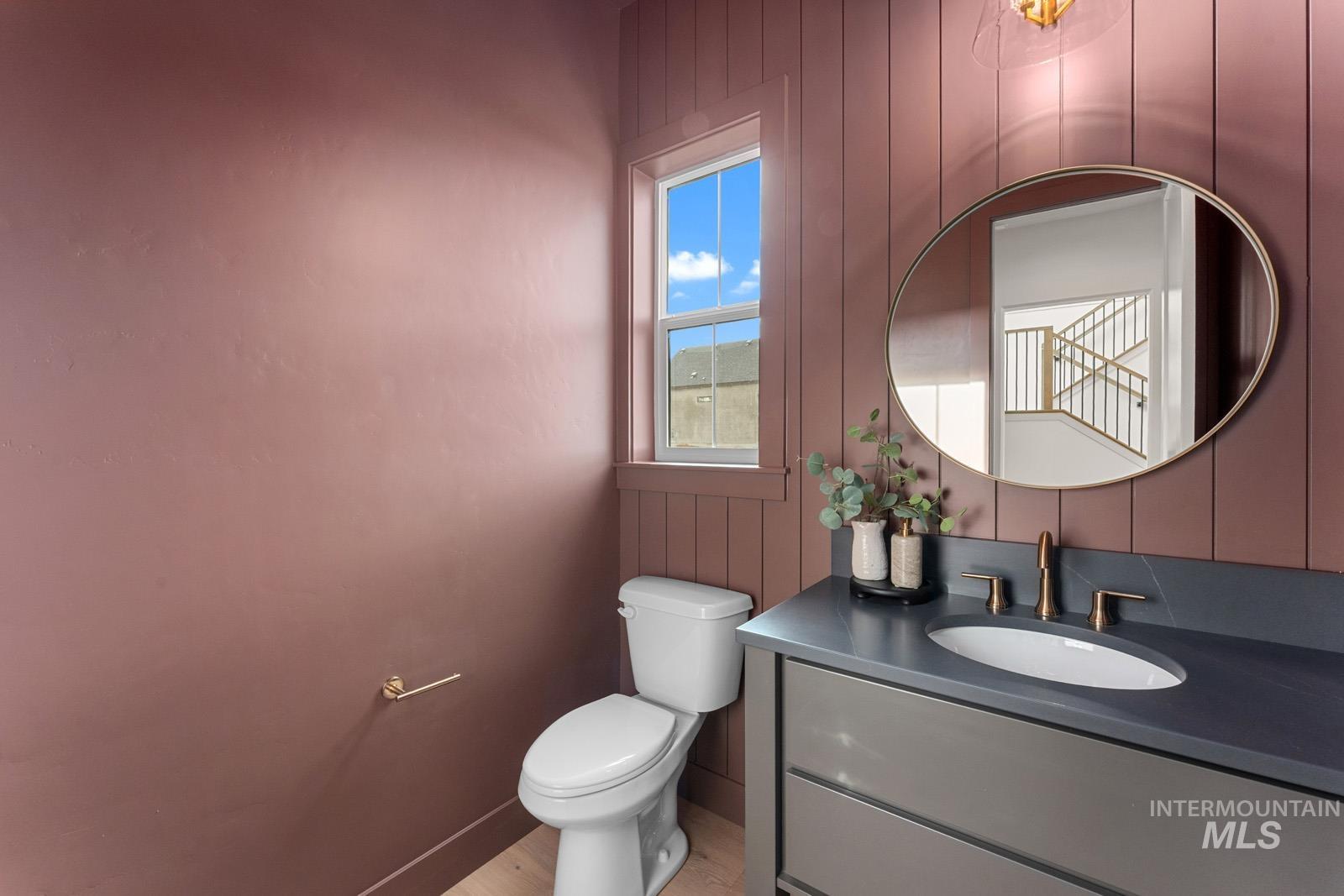 Half bathroom with vanity, wooden walls, and light wood-type flooring