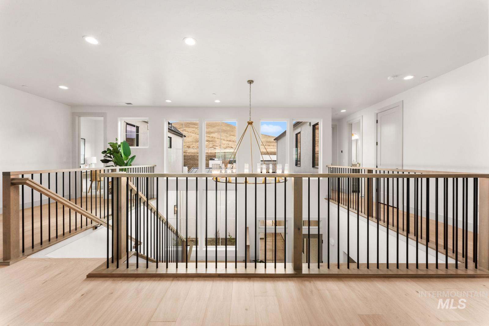 Hall featuring an upstairs landing, wood finished floors, and hanging lights