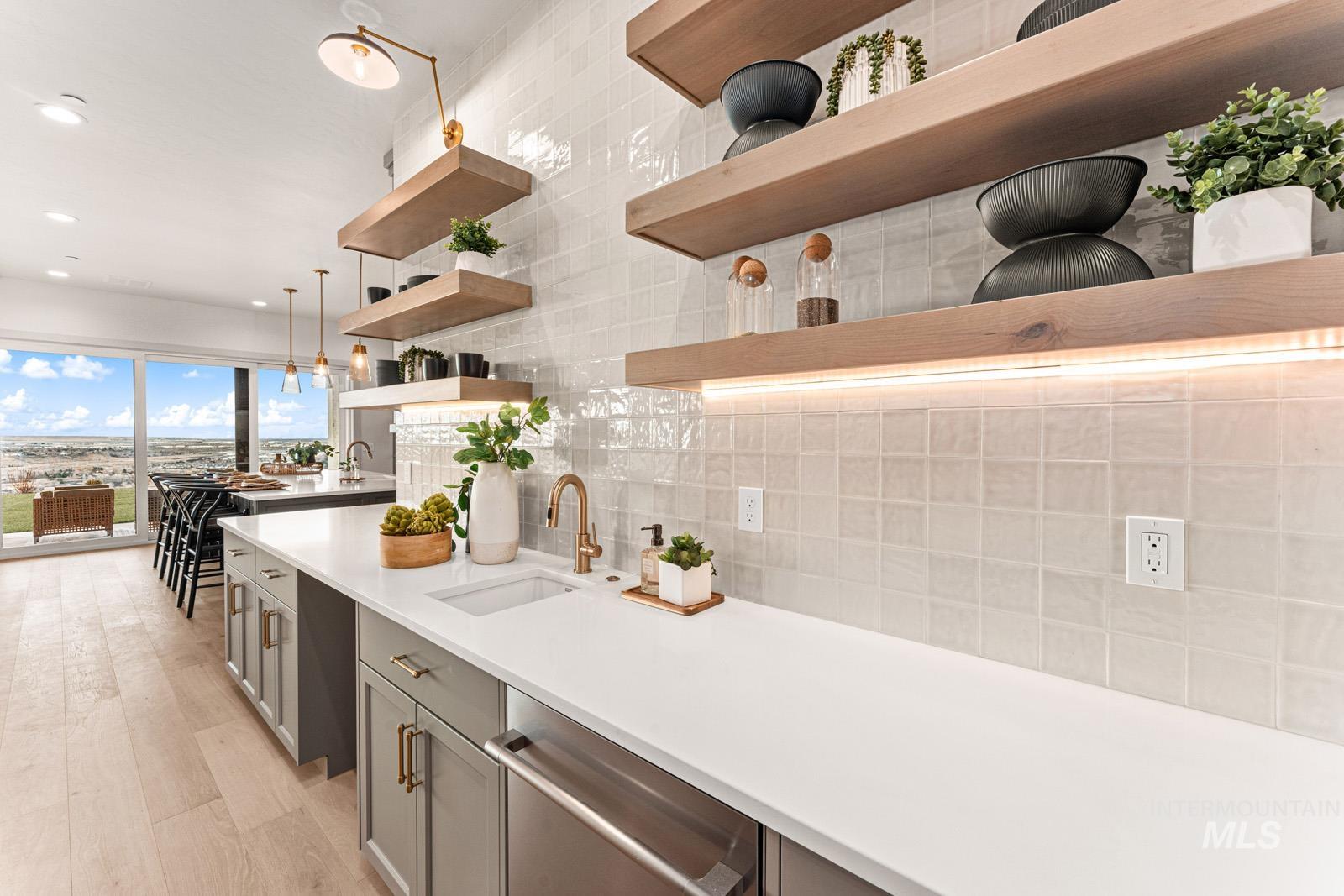 Kitchen with decorative light fixtures, stainless steel dishwasher, light stone countertops, and tasteful backsplash