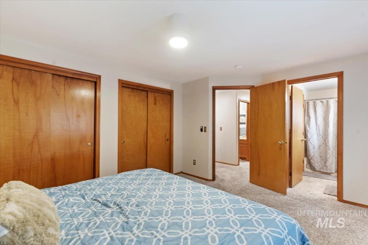 Bedroom featuring two closets, light carpet, and ensuite bathroom