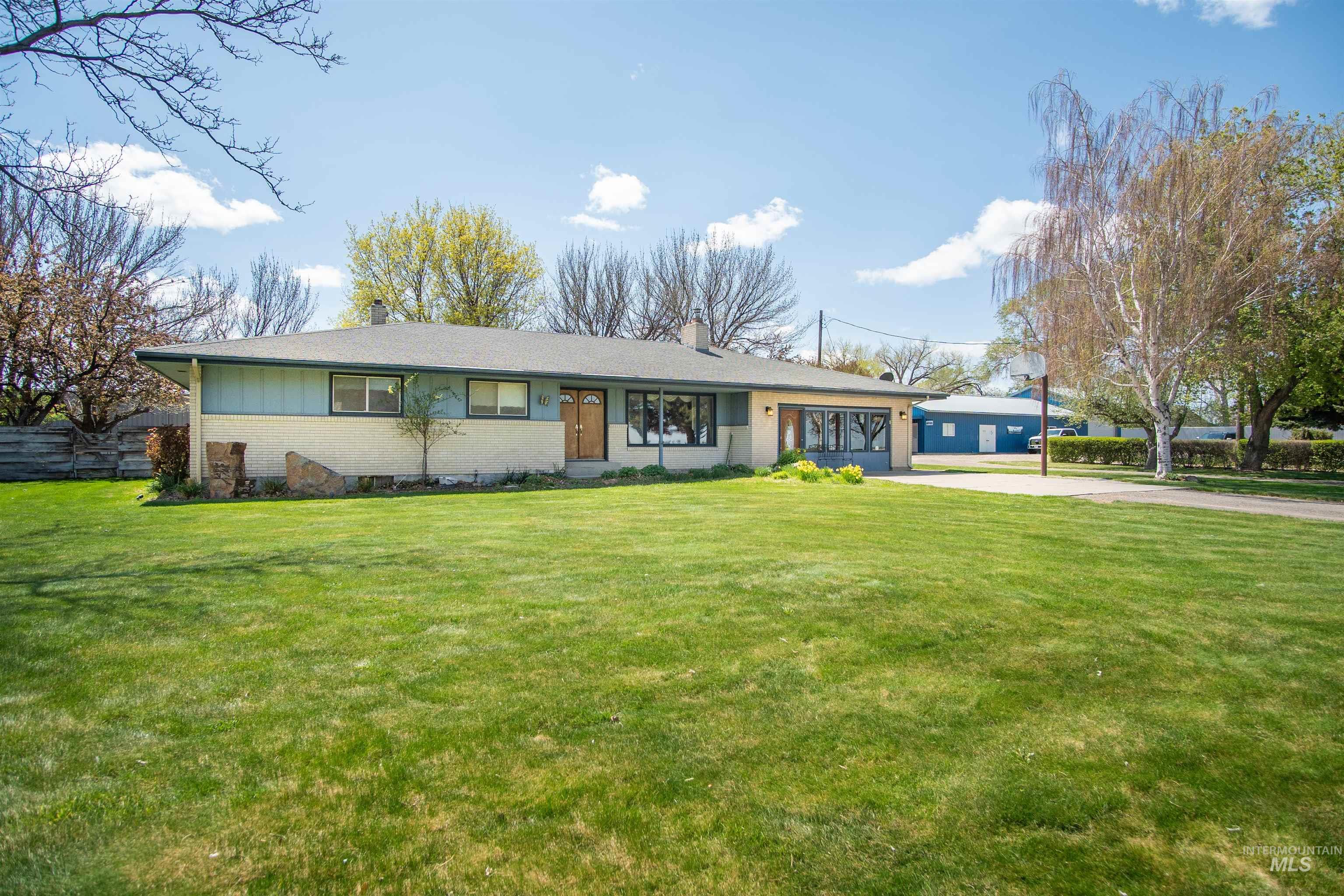 Ranch-style house featuring driveway, brick siding, a front lawn, and a chimney
