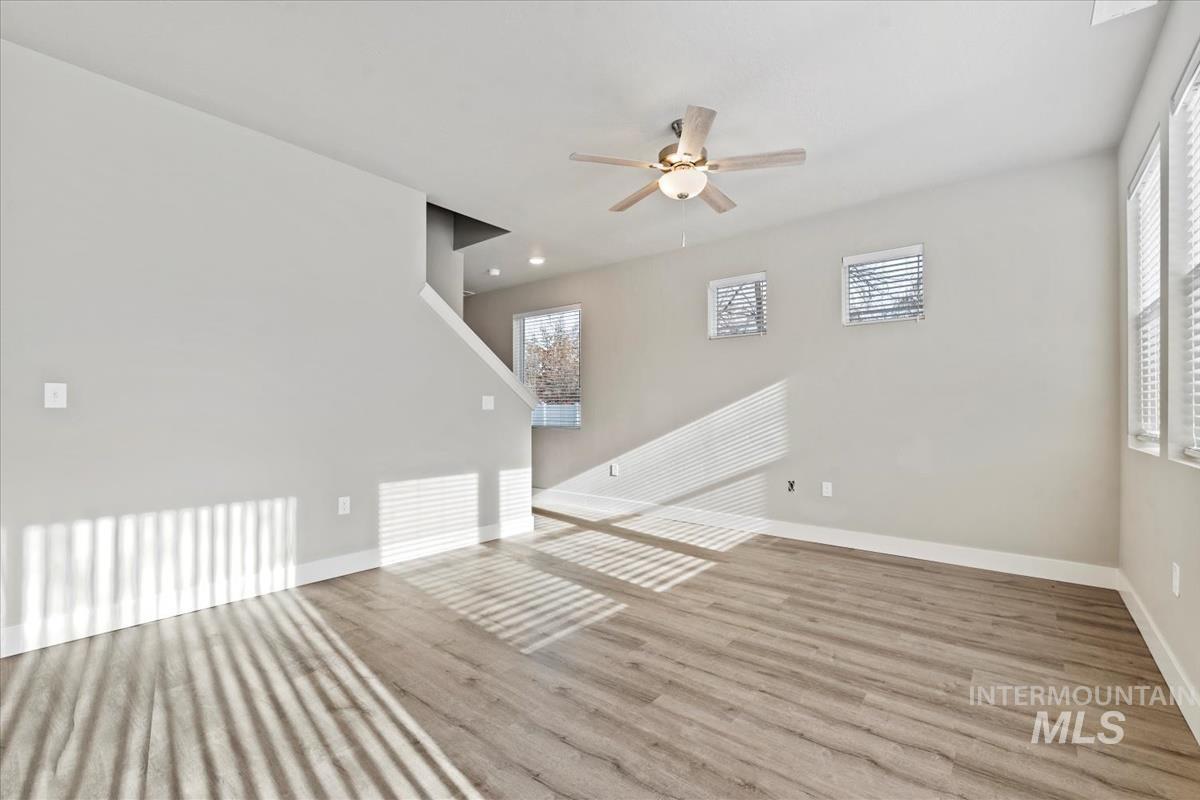 Unfurnished living room featuring wood finished floors and a ceiling fan