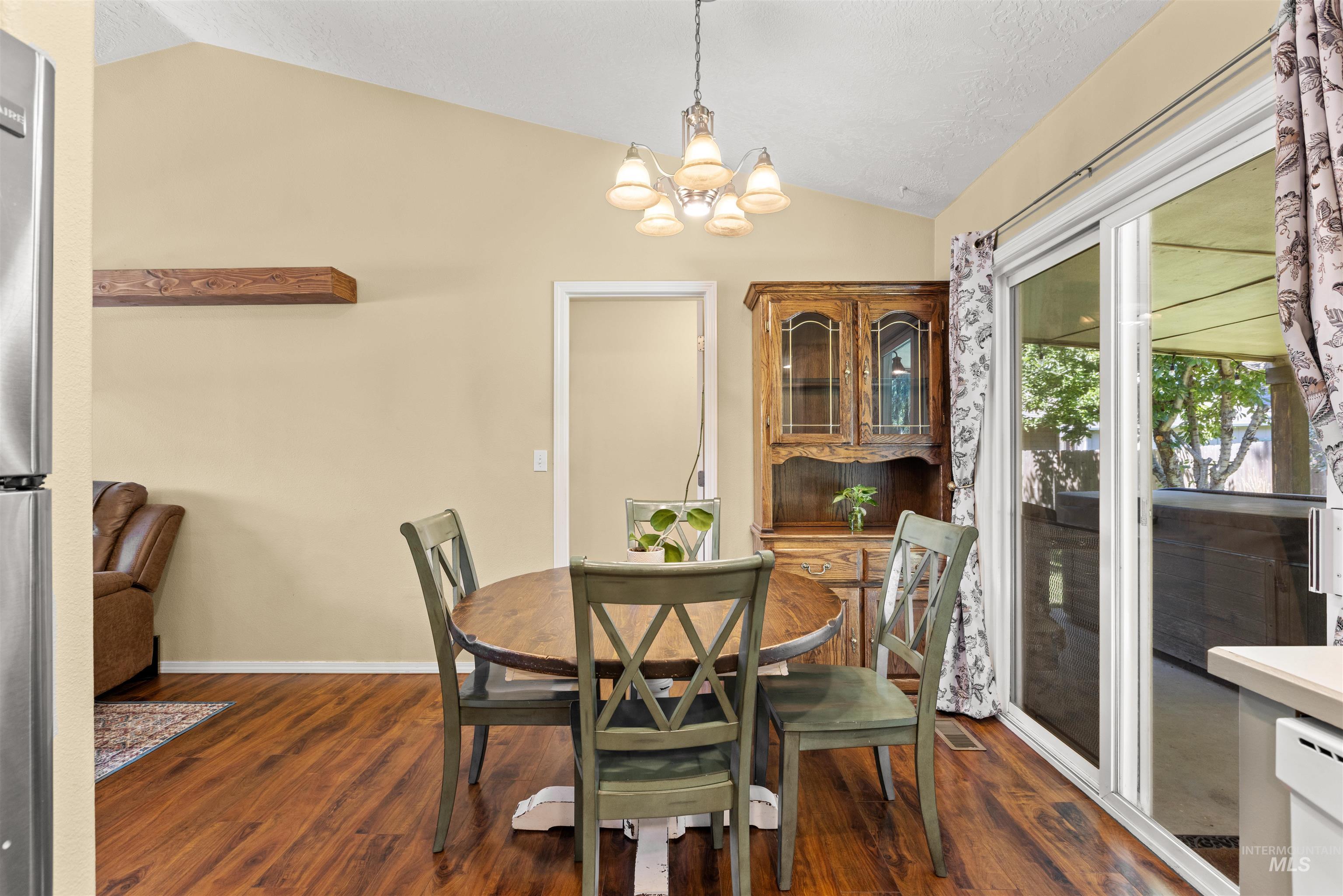 Dining area featuring vaulted ceilings, wood-finish flooring, a built-in floating shelf, and sliding glass doors