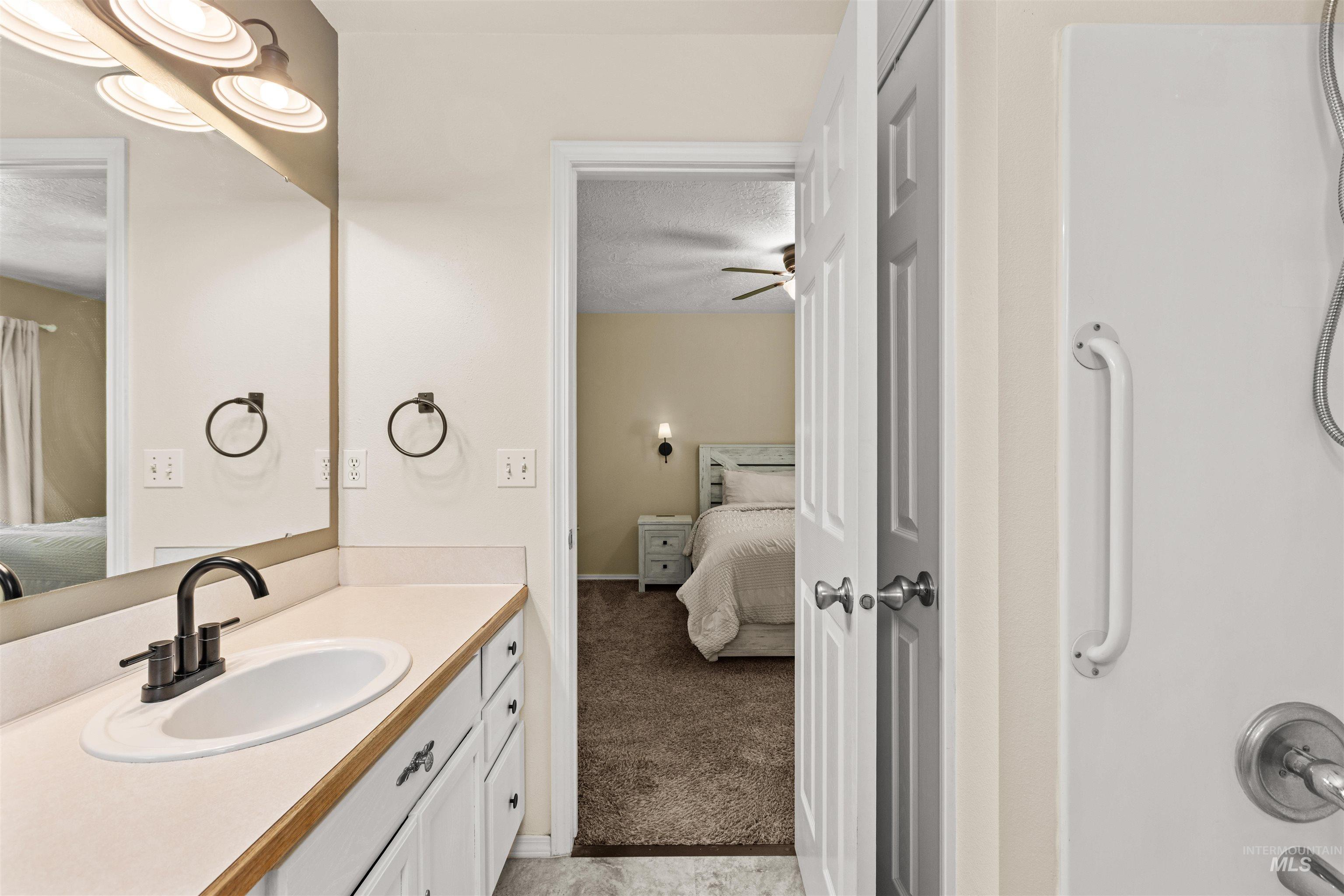 Bathroom vanity featuring a single sink, dark-finish faucet, and a large mirror with overhead lighting