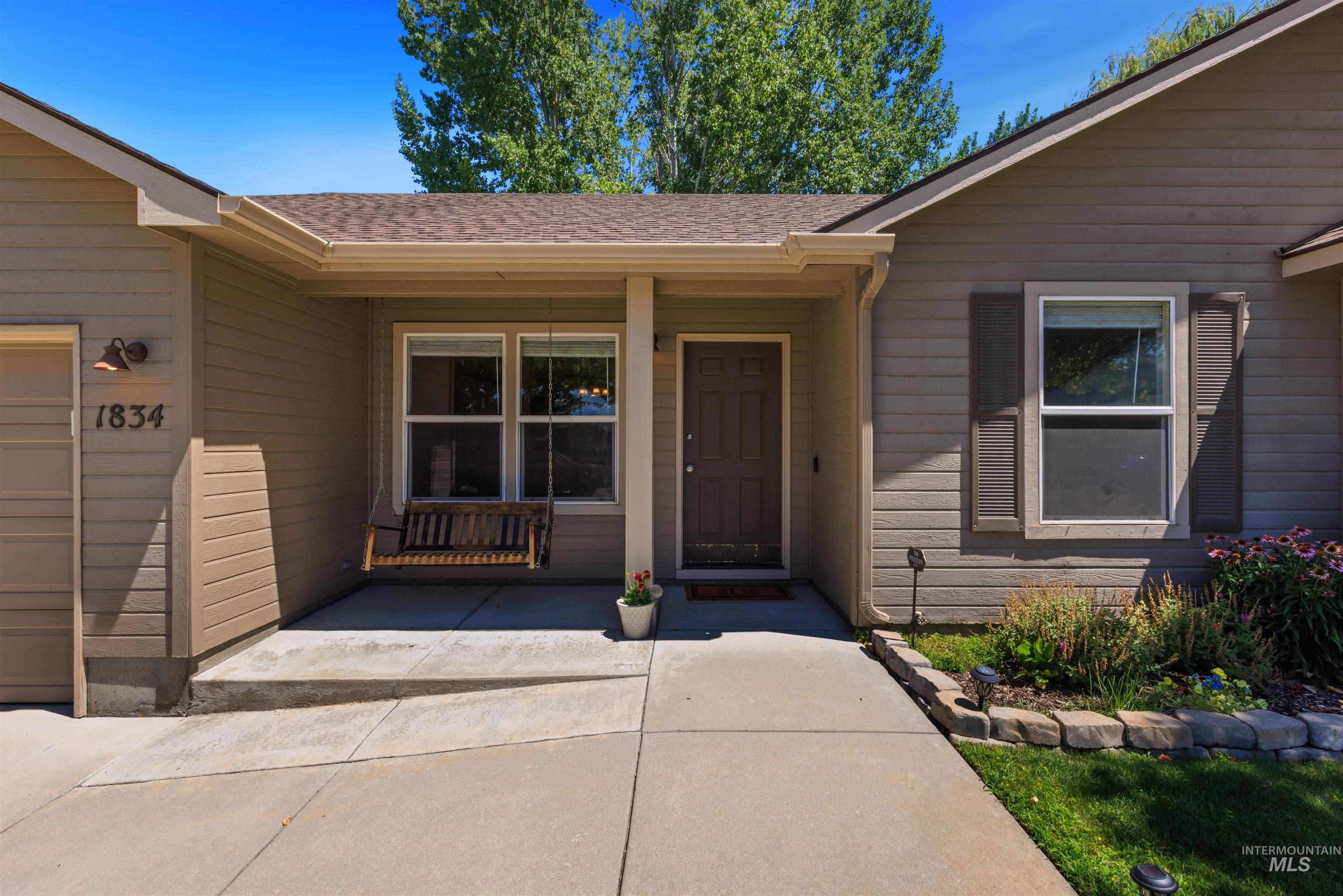 Front exterior featuring neutral-toned siding, a covered porch entry, and a dark brown paneled front door