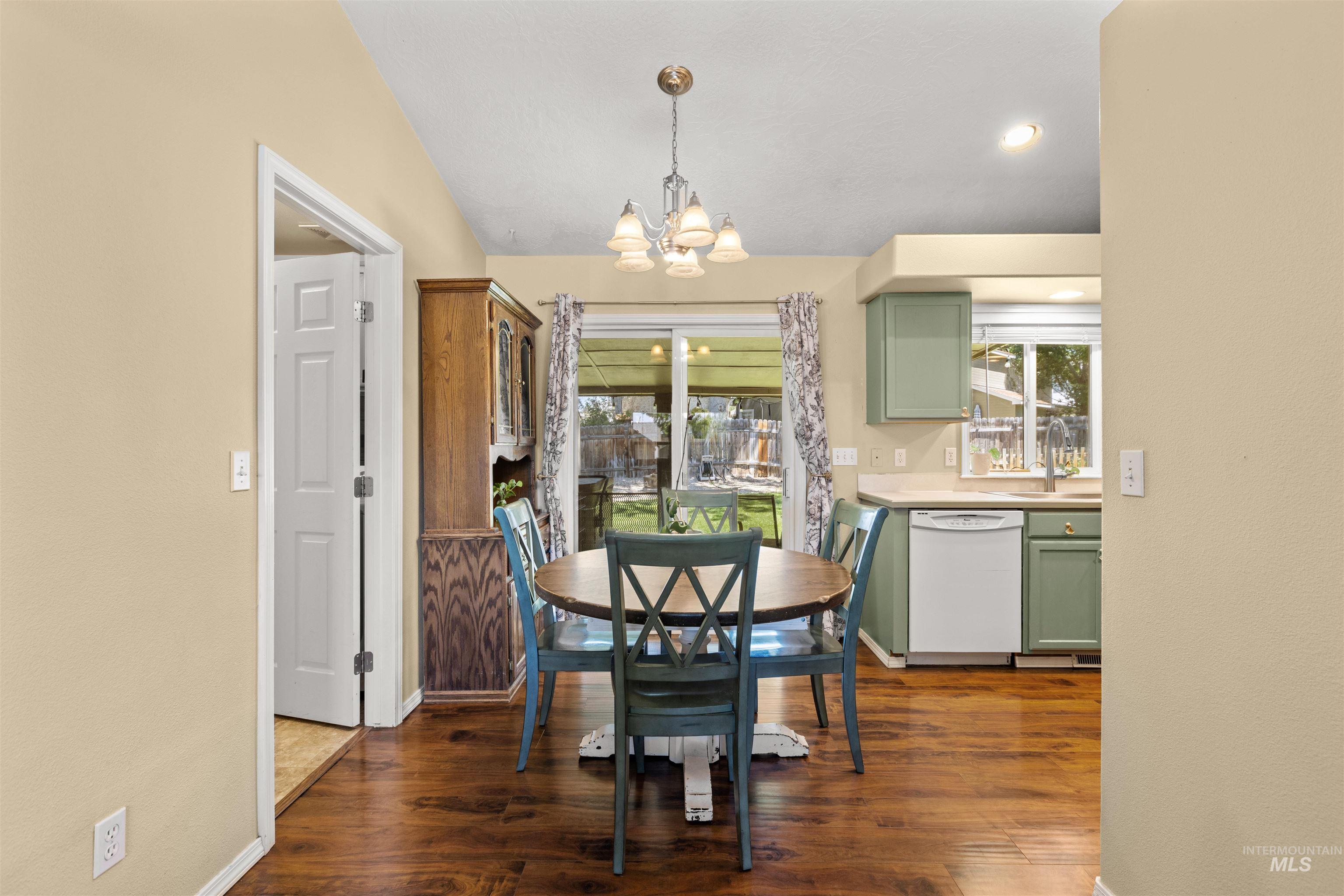 Dining area featuring wood-finish flooring, a contemporary chandelier, and direct patio access through a glass slider
