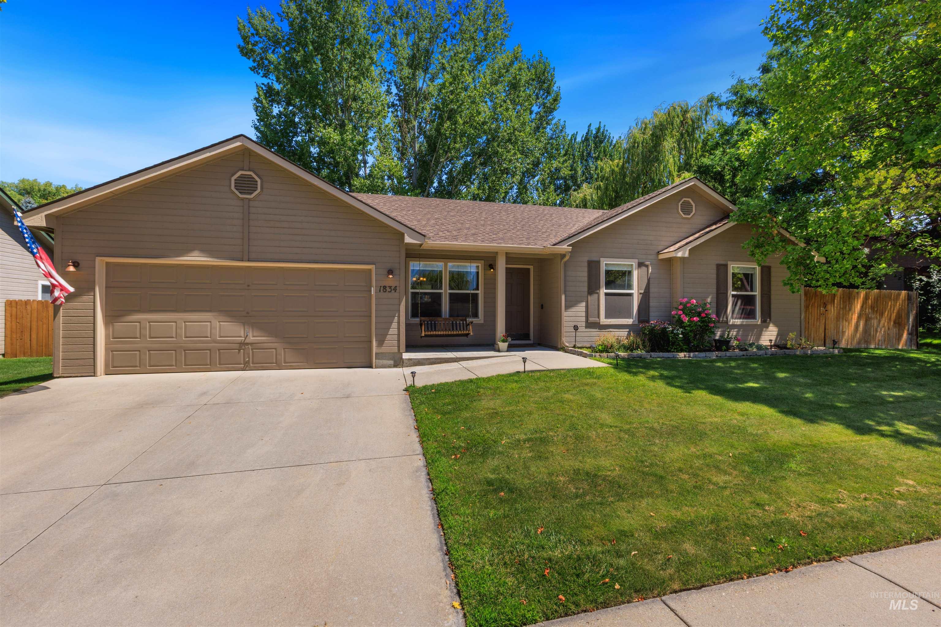 Single-story residence featuring a two-car garage, concrete driveway, and a front yard with established landscaping