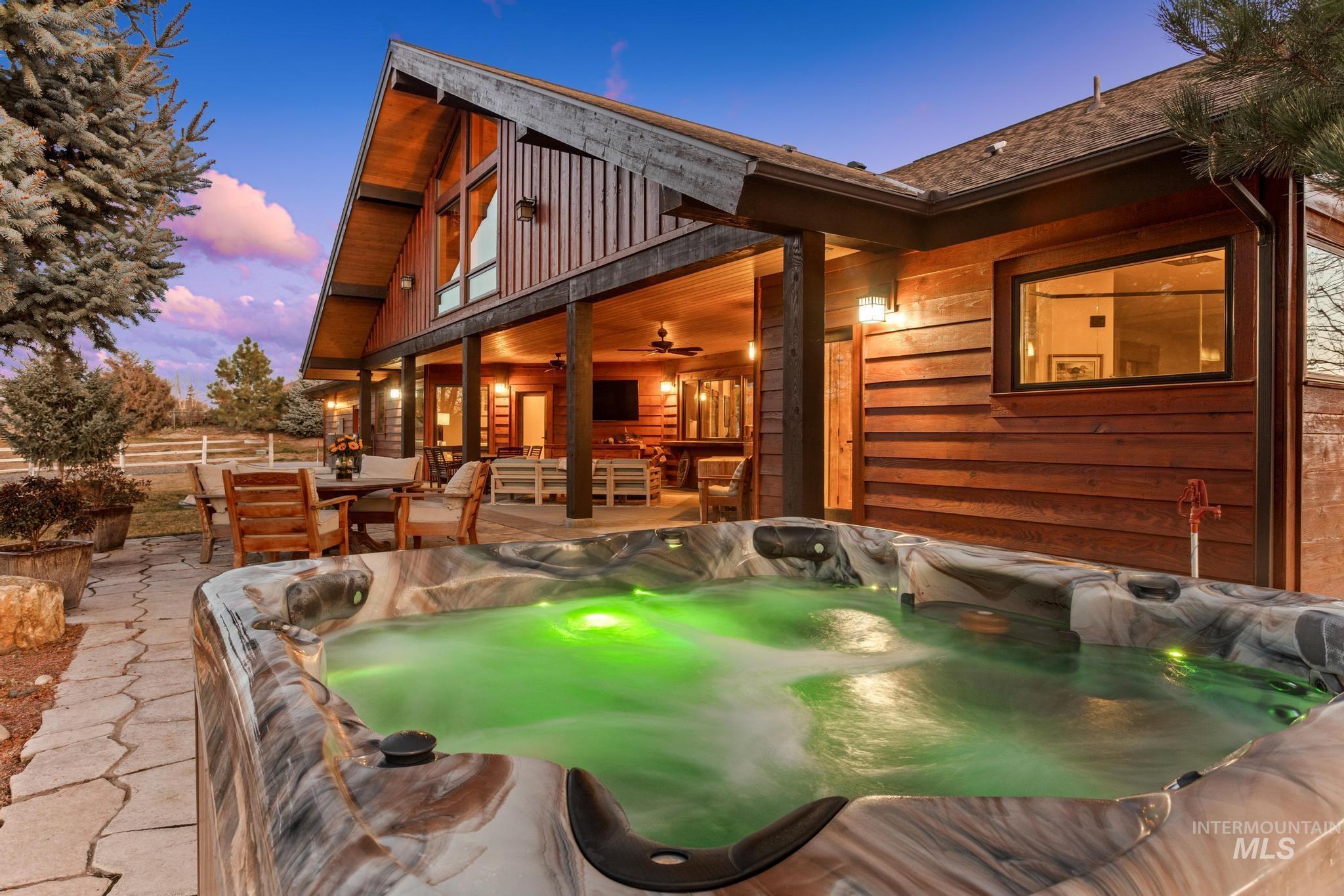 View of patio from hot tub with direct access to master suite. Surrounded by trees ensuring privacy