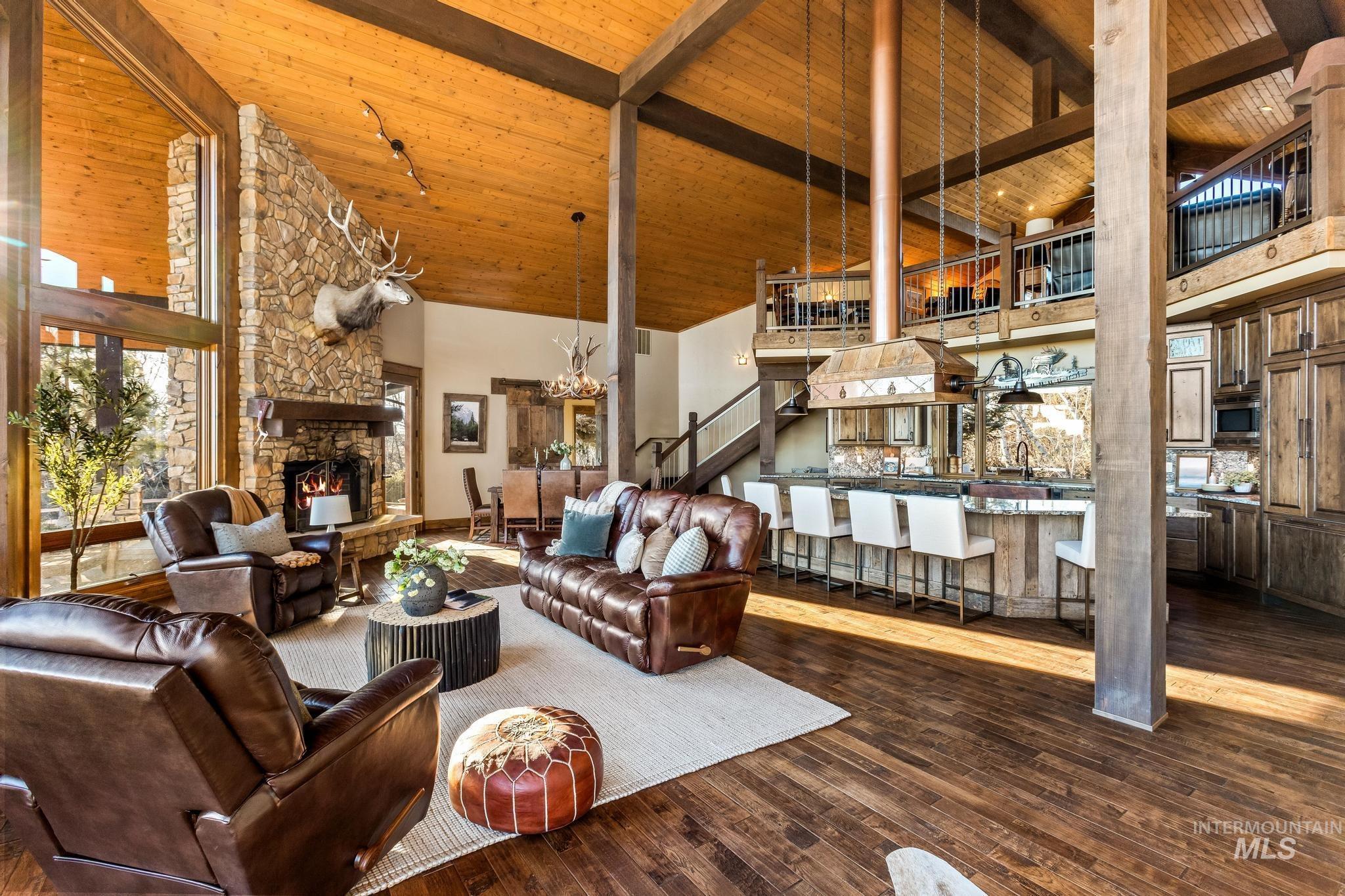 Great Room with hickory flooring, wood-beamed ceiling, stone fireplace, and suspended lighting