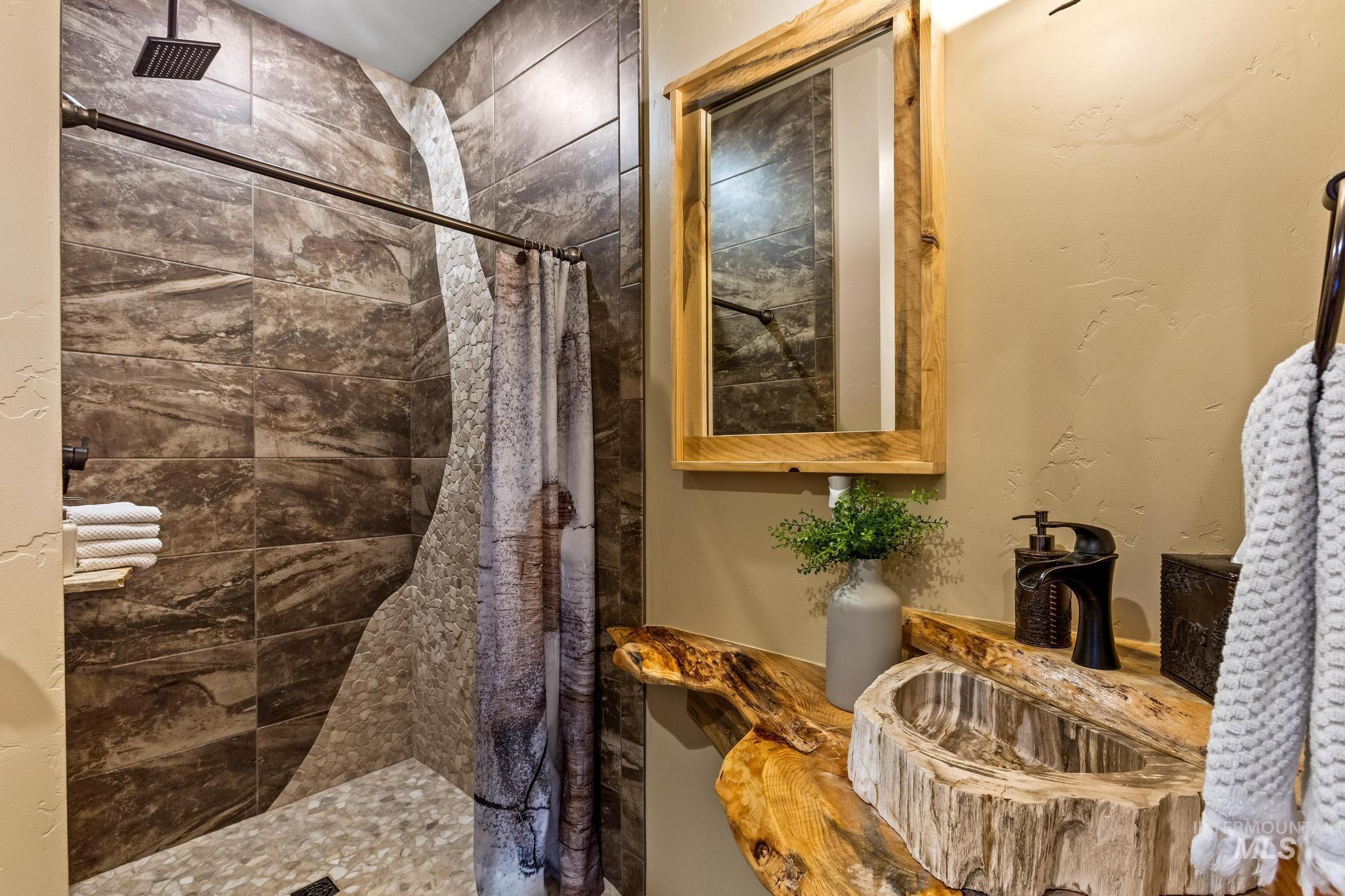 Full bath featuring a walk-in/roll-in shower with custom tile work, milled wood countertop, custom made petrified wood sink.