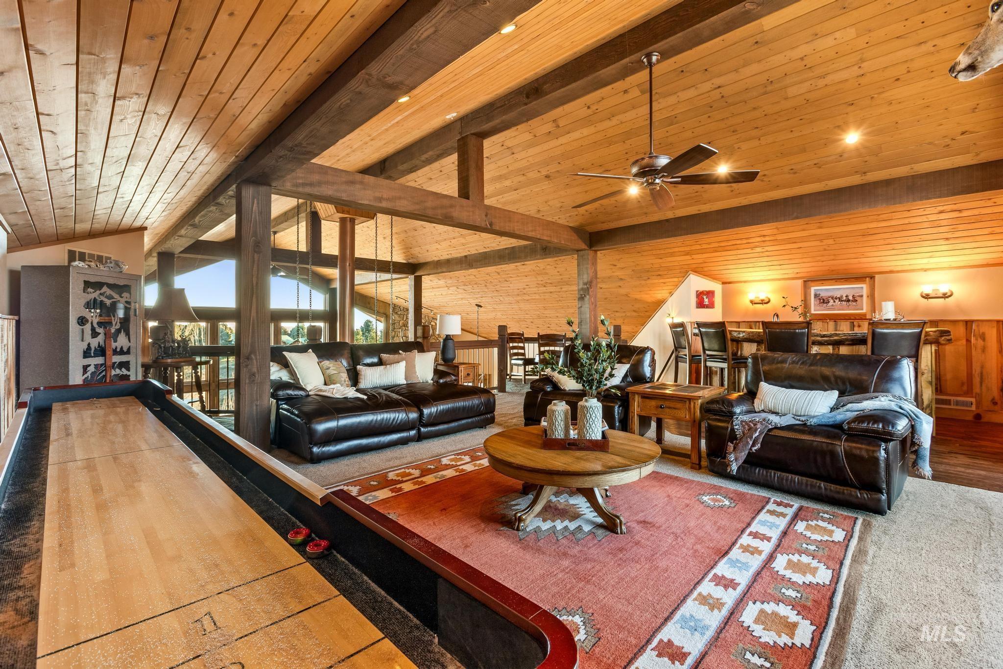 Open loft featuring peaked wood ceiling with exposed beams, ceiling fan, custom milled bar, open to great room below