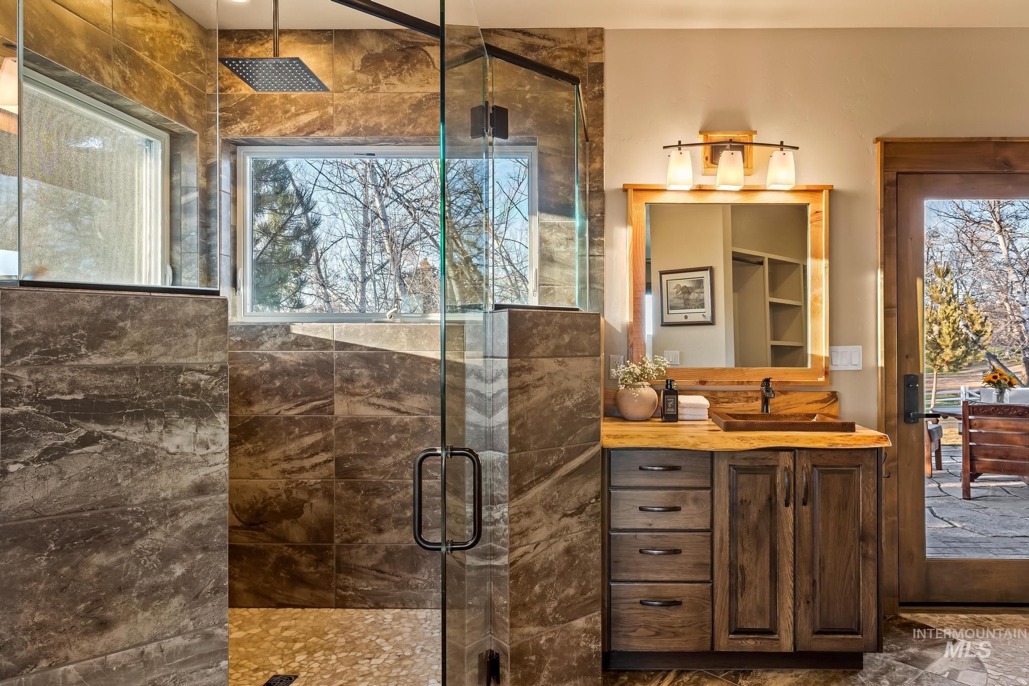Master bathroom featuring dual vanities, custom milled wood counters, copper sinks, walk-in shower, back patio access to hot tub and tons of natural light