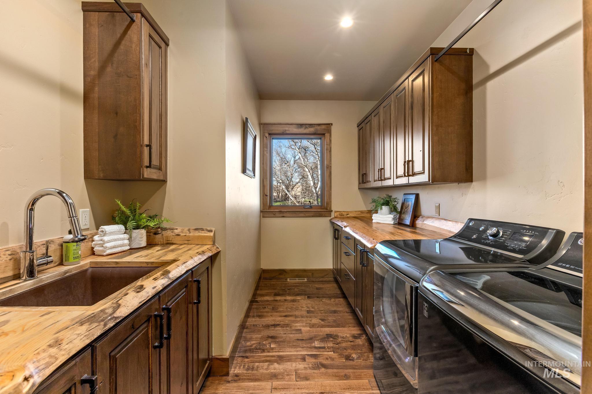 Laundry area featuring included washer and dryer, ample custom cabinets with sink, and custom wood counters