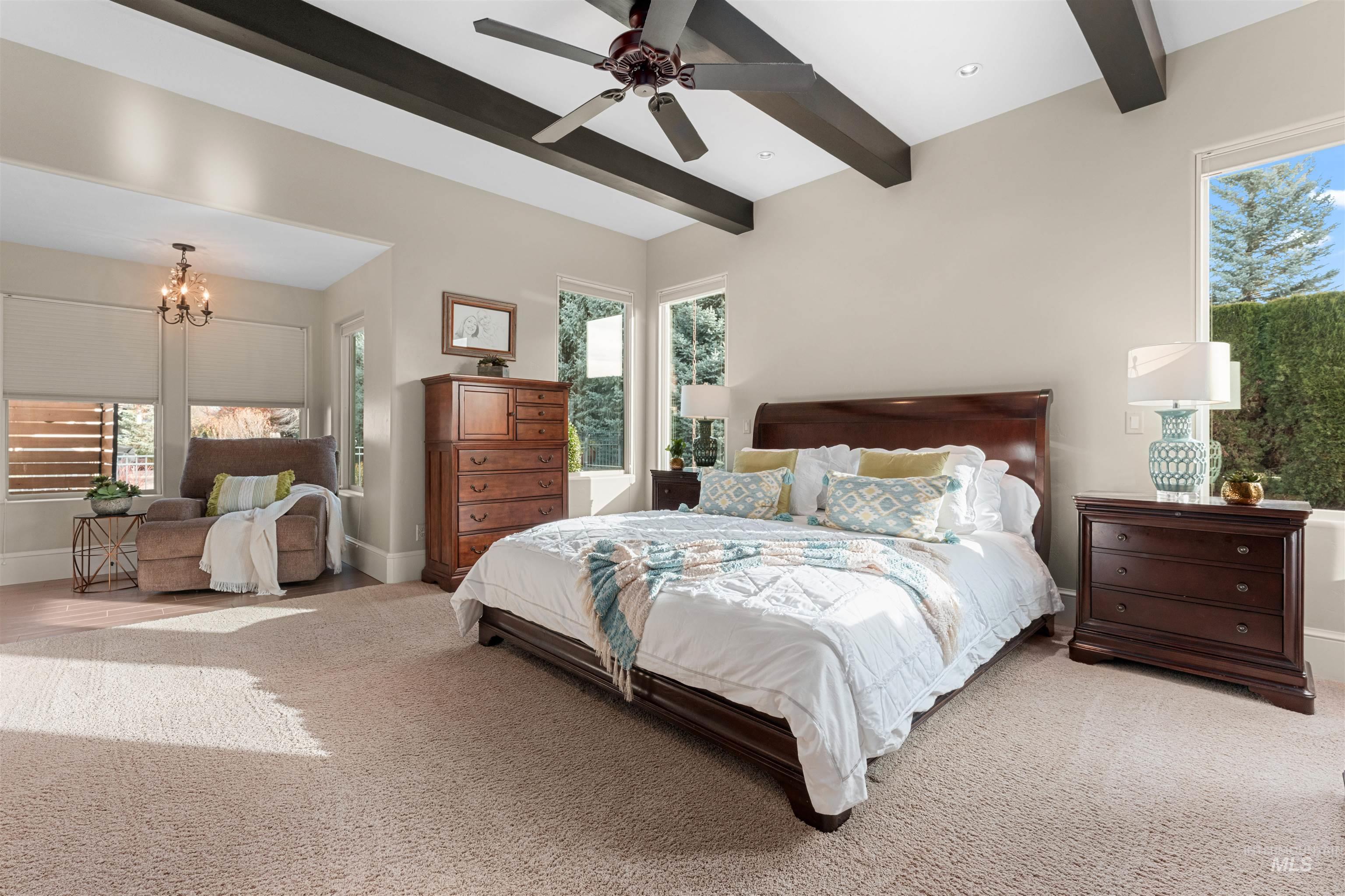 Carpeted bedroom with multiple windows, beam ceiling, a chandelier, and a ceiling fan