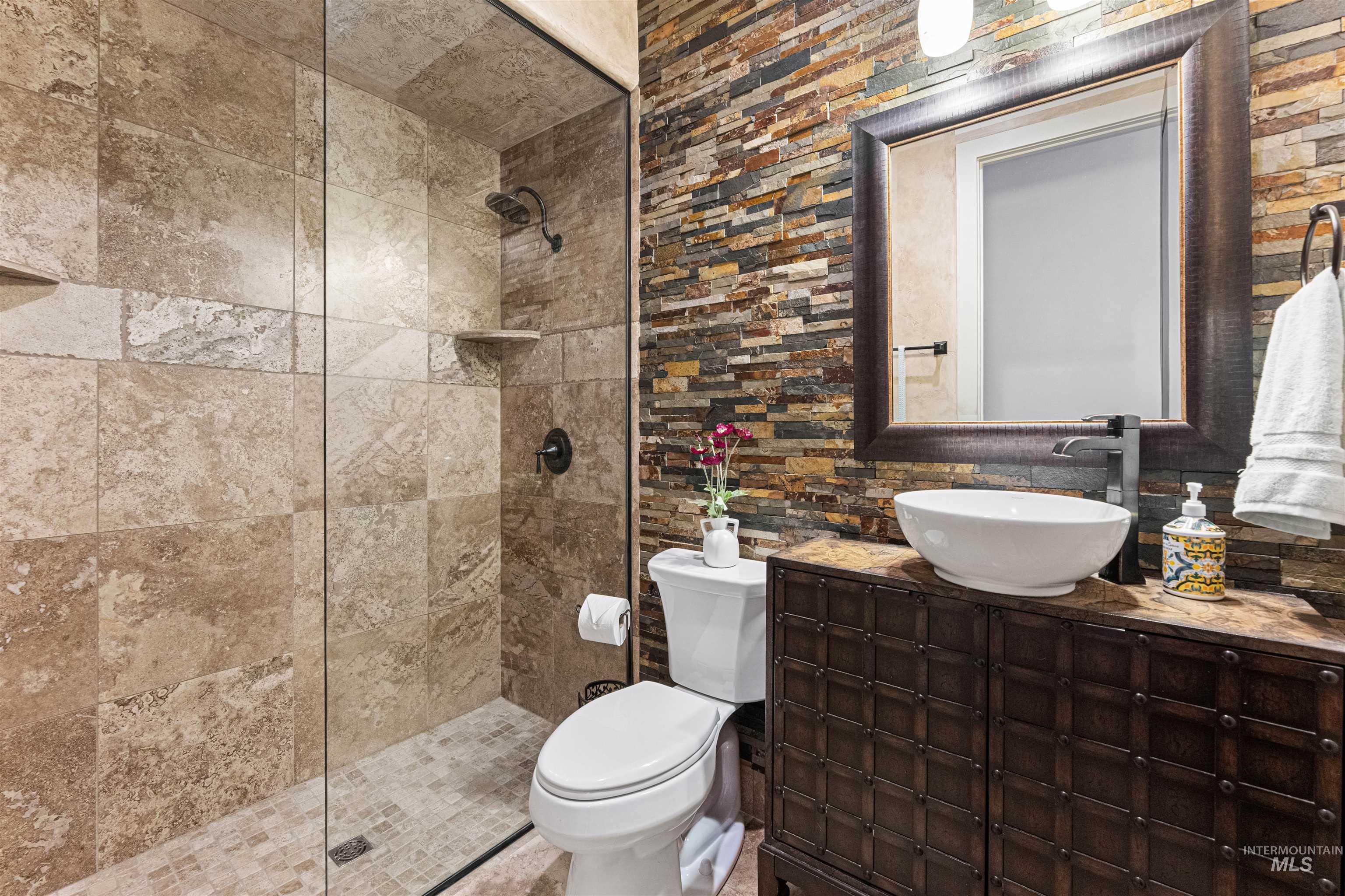 Full bathroom with vanity, walk in shower, and tasteful backsplash