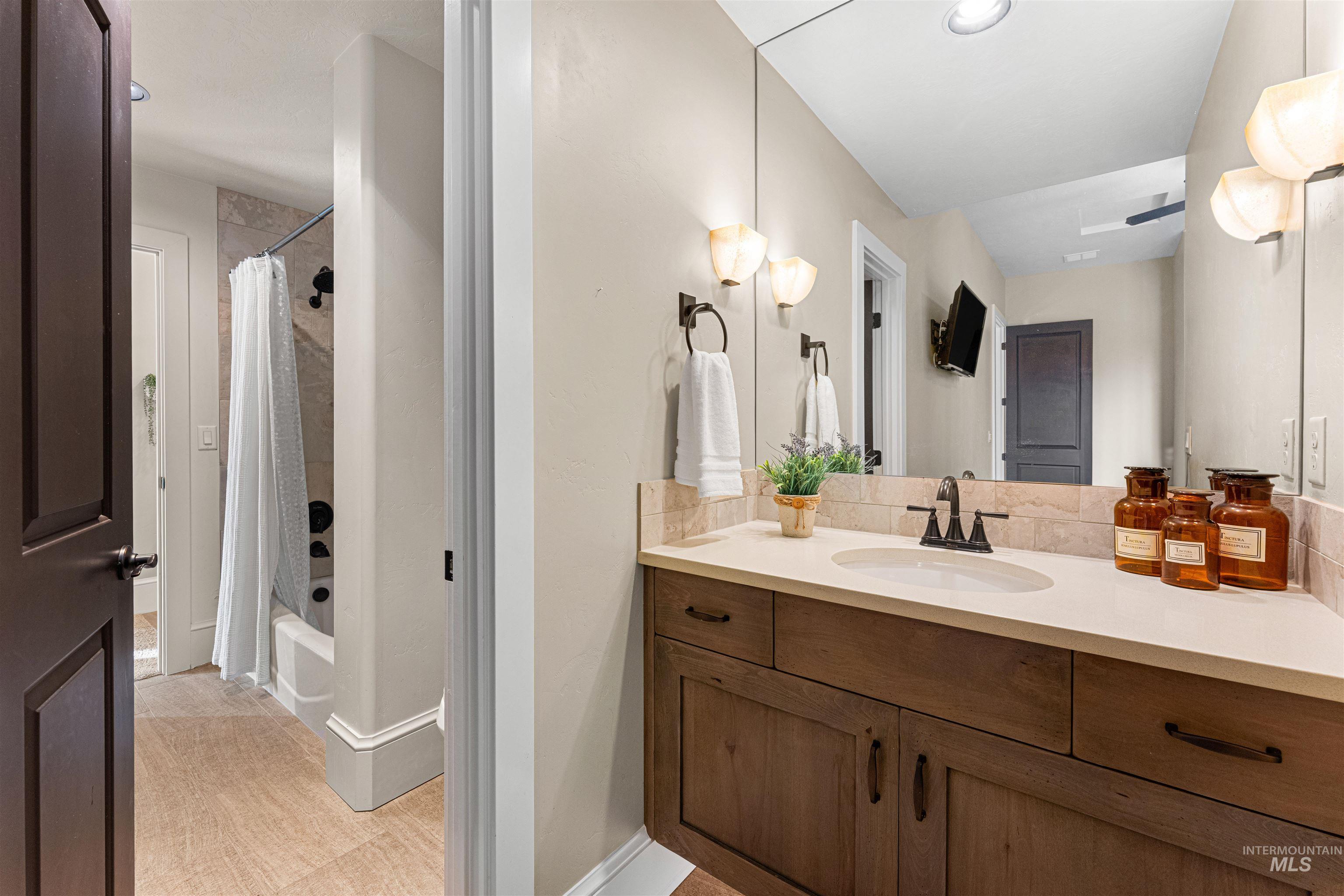 Bathroom featuring shower / bathtub combination with curtain, vanity, and light tile patterned floors