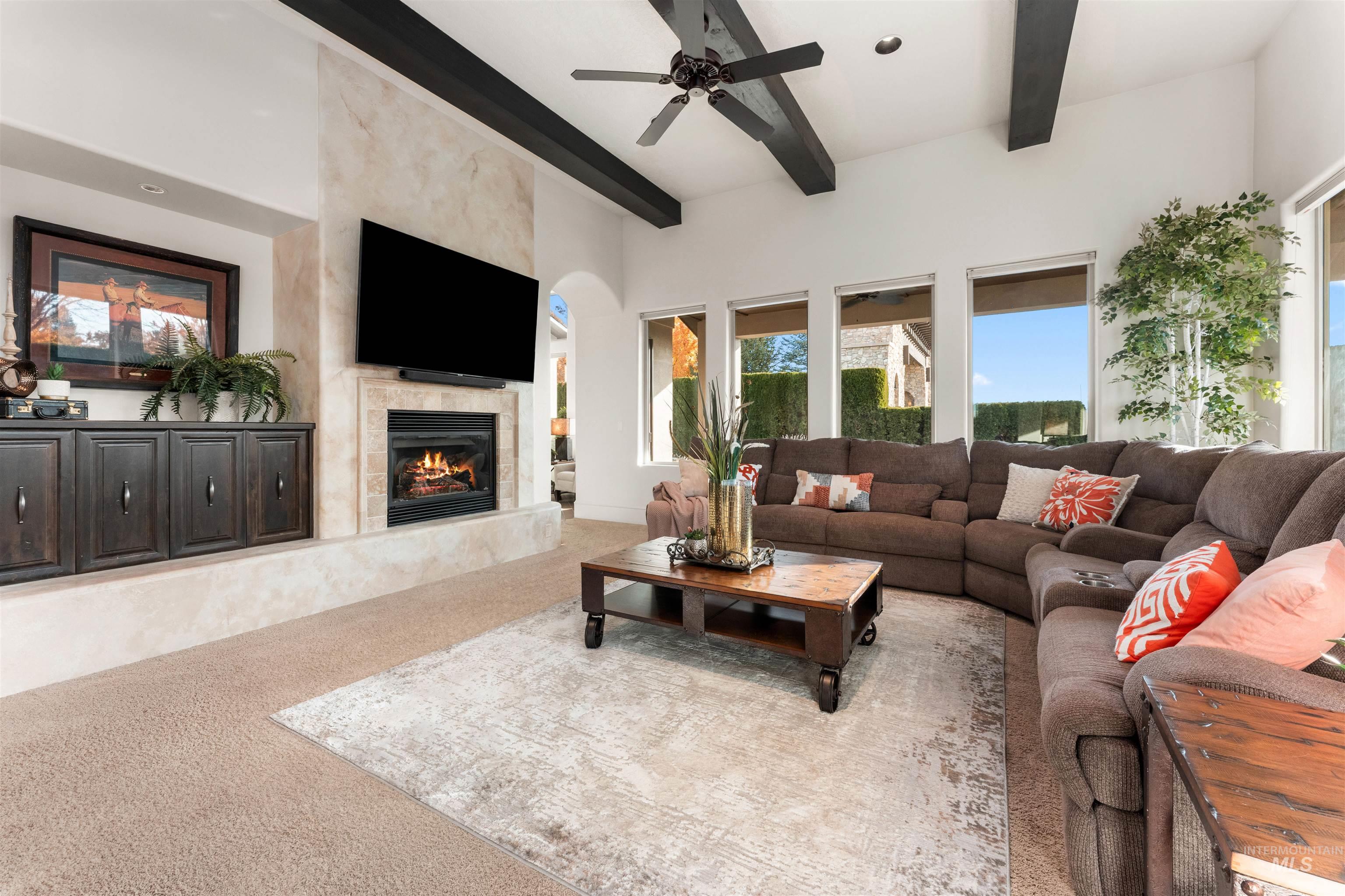 Living room featuring beamed ceiling, light carpet, a premium fireplace, a ceiling fan, and recessed lighting