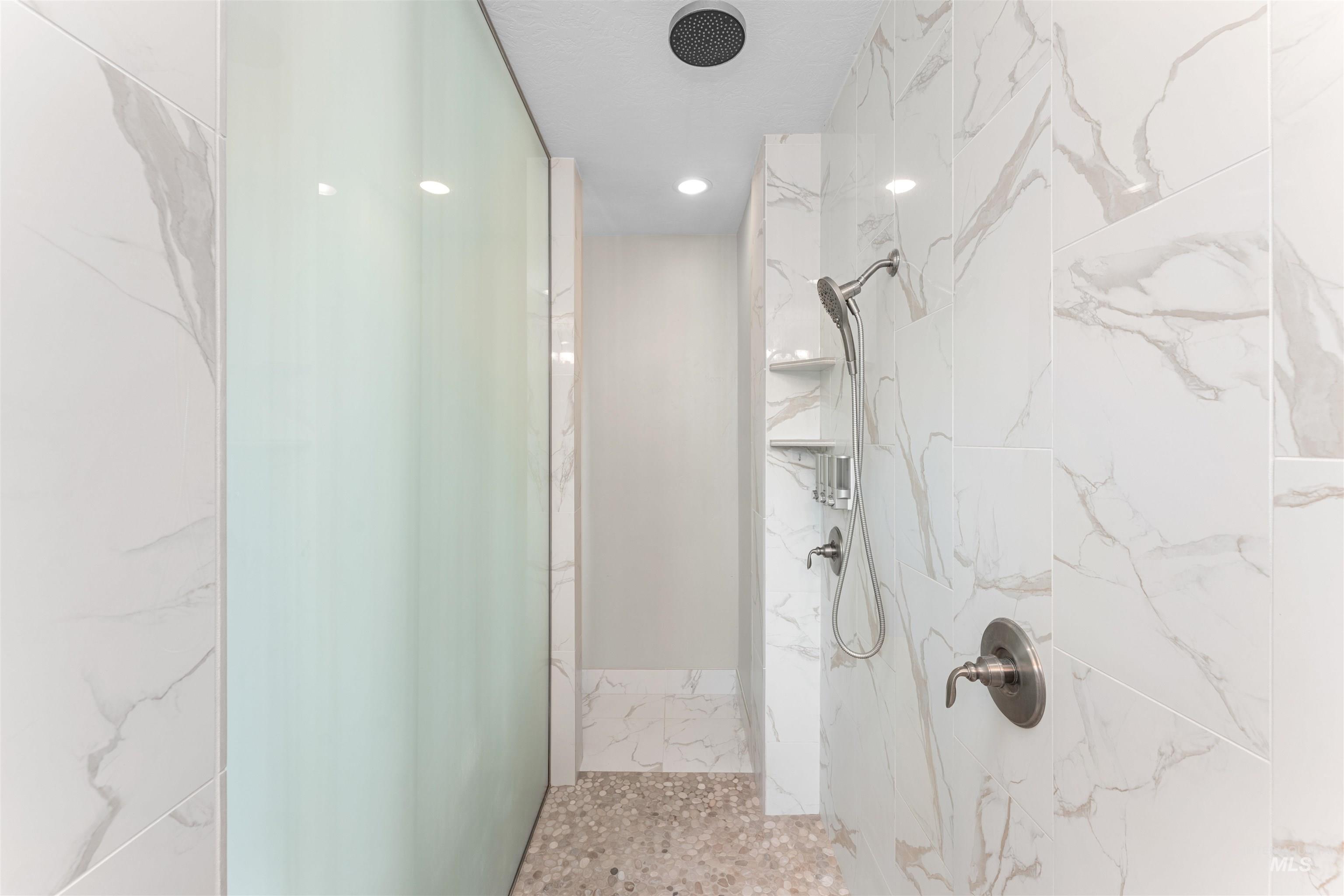 Bathroom with a marble finish shower and recessed lighting
