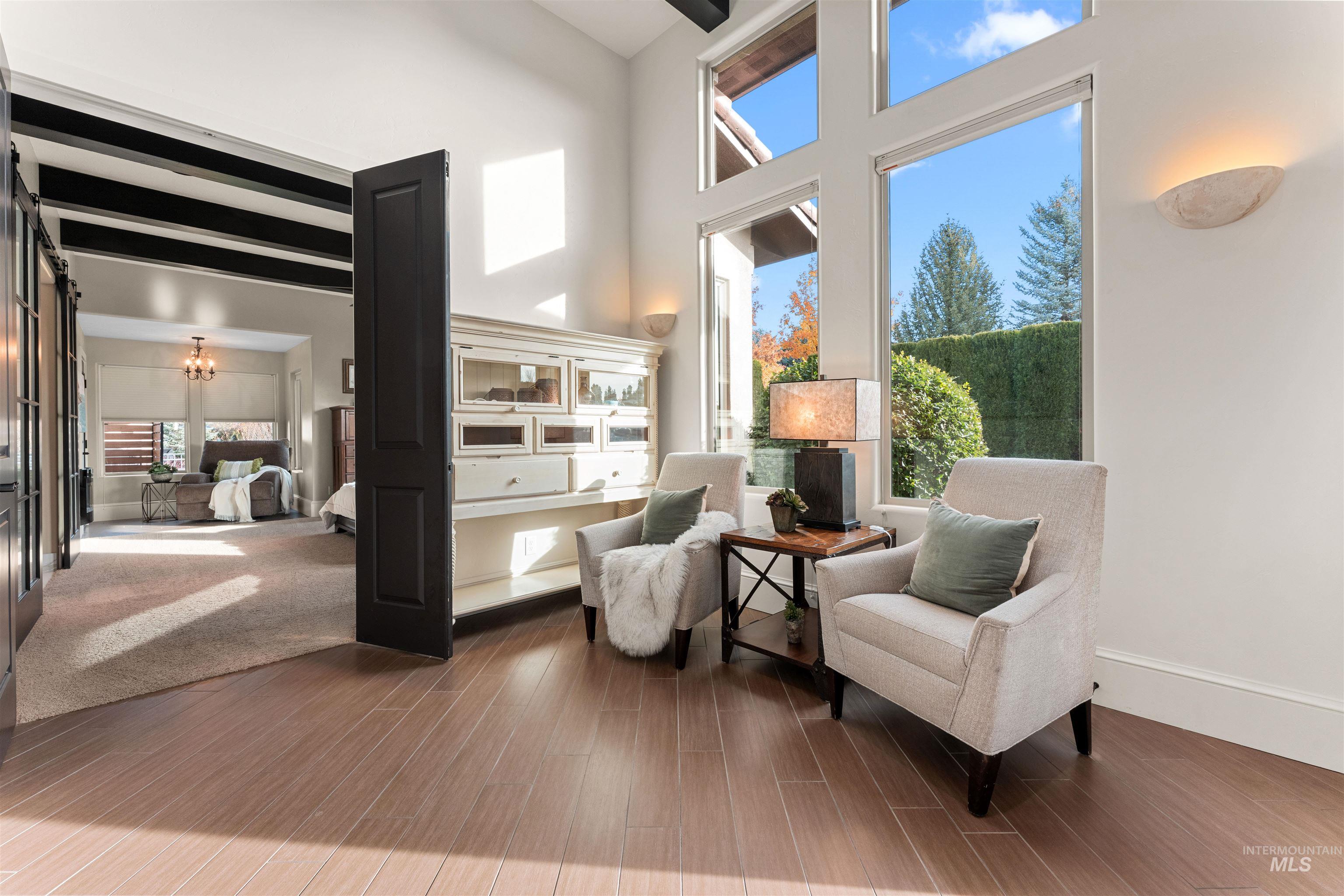 Living area with a chandelier, dark wood-style flooring, and a towering ceiling