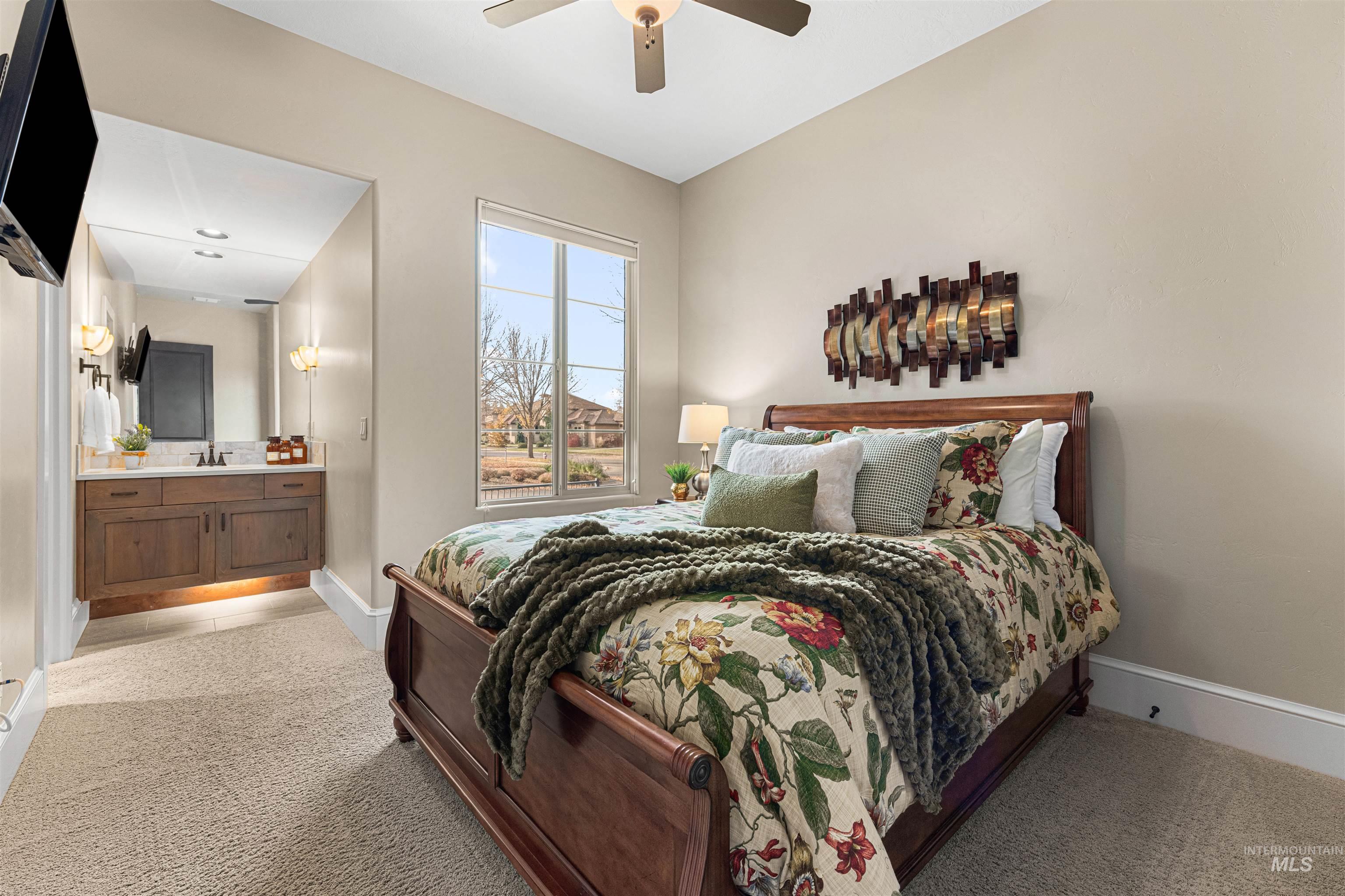 Bedroom with light colored carpet, a ceiling fan, and connected bathroom