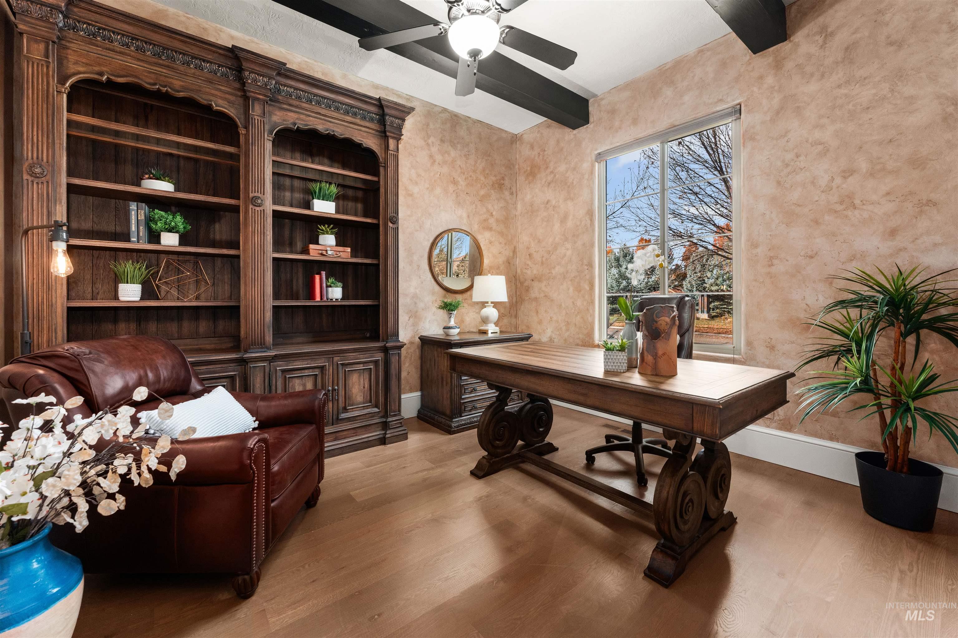 Home office featuring beamed ceiling, light wood finished floors, and a ceiling fan