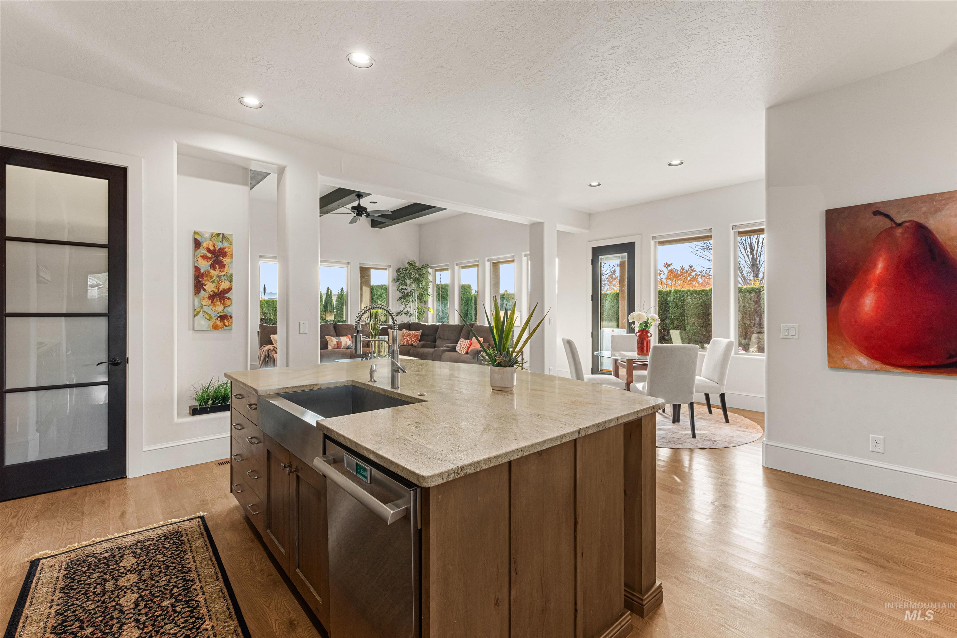 Kitchen featuring light stone countertops, light wood finished floors, ceiling fan, stainless steel dishwasher, and dark brown cabinets