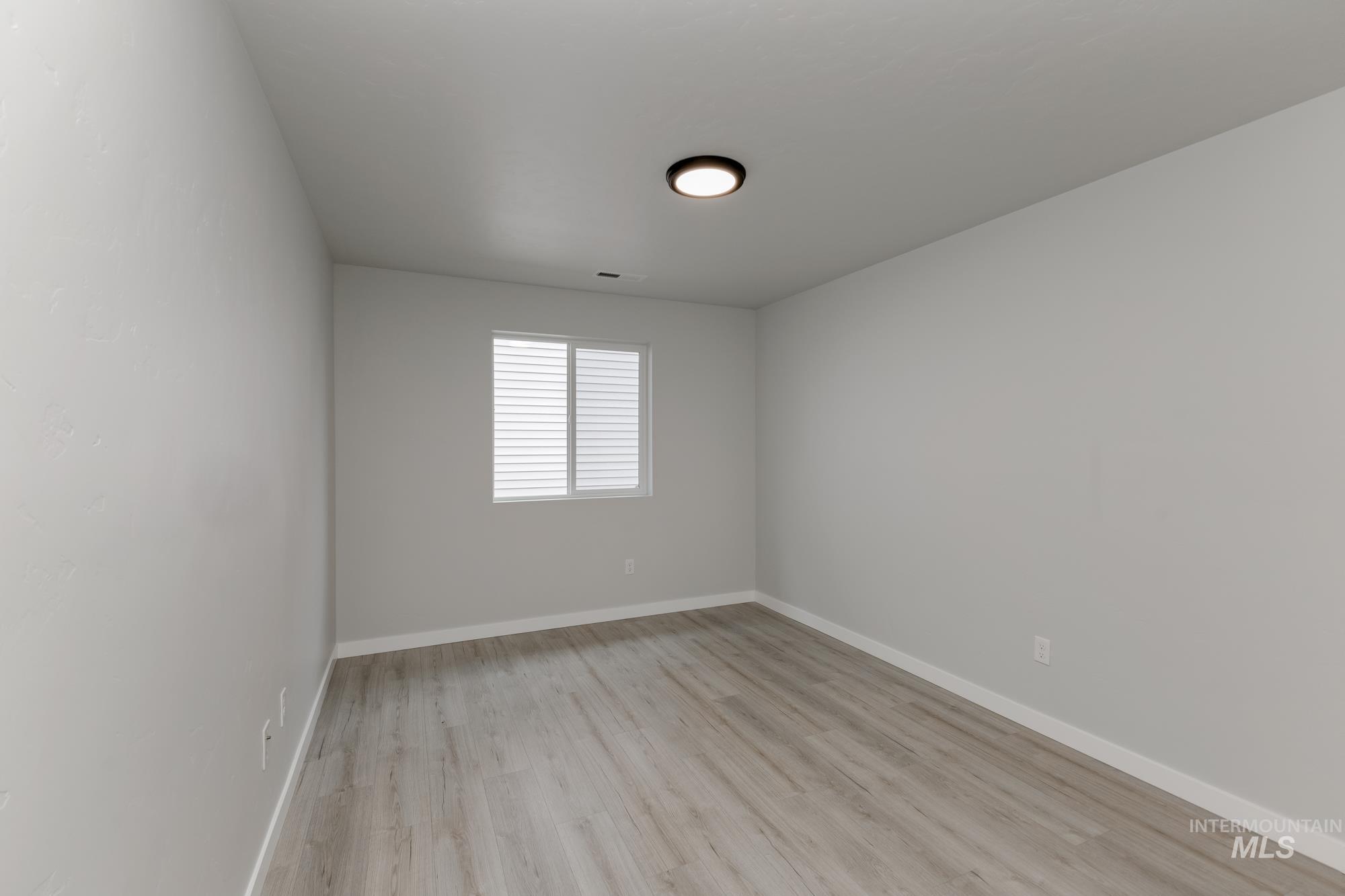 Spare room featuring light wood-style flooring and baseboards