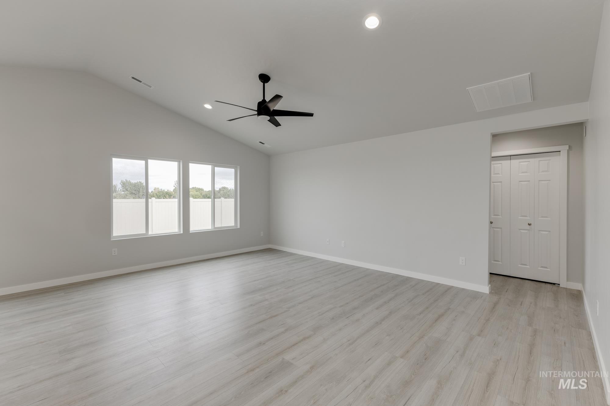 Empty room featuring light wood-type flooring, vaulted ceiling, recessed lighting, and a ceiling fan