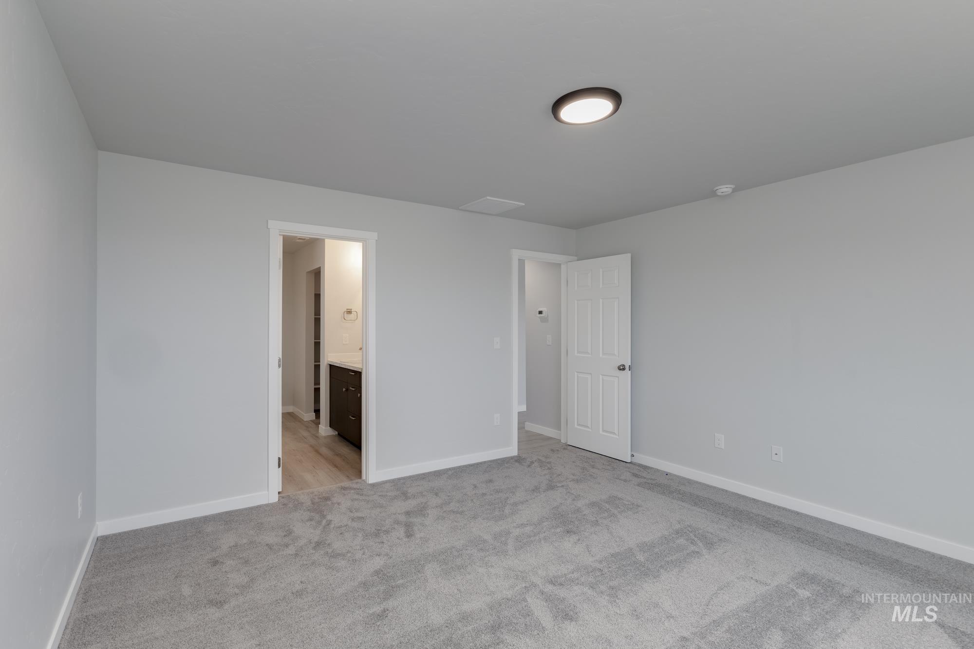 Unfurnished bedroom featuring light carpet and ensuite bathroom