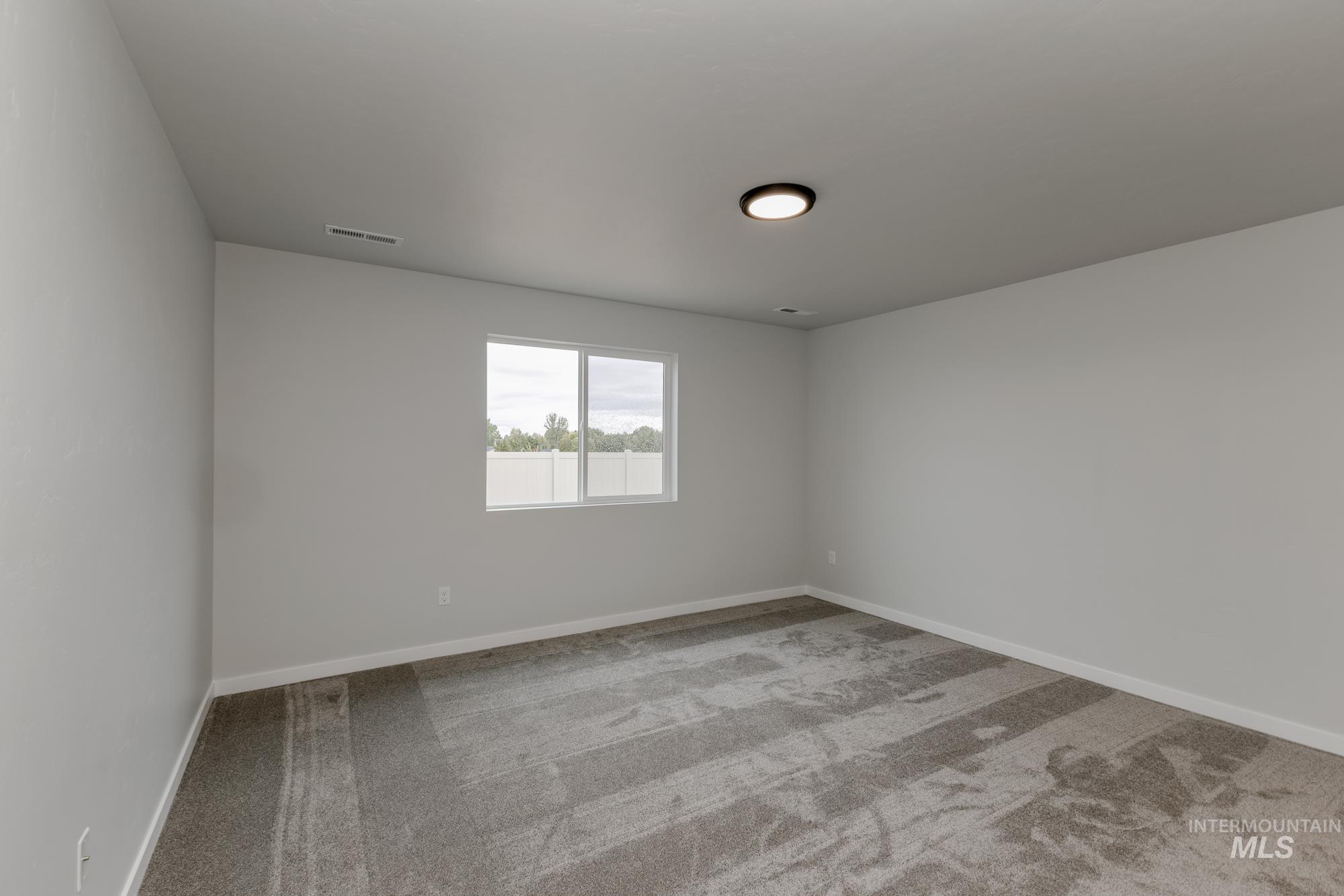 Spare room featuring light colored carpet and baseboards