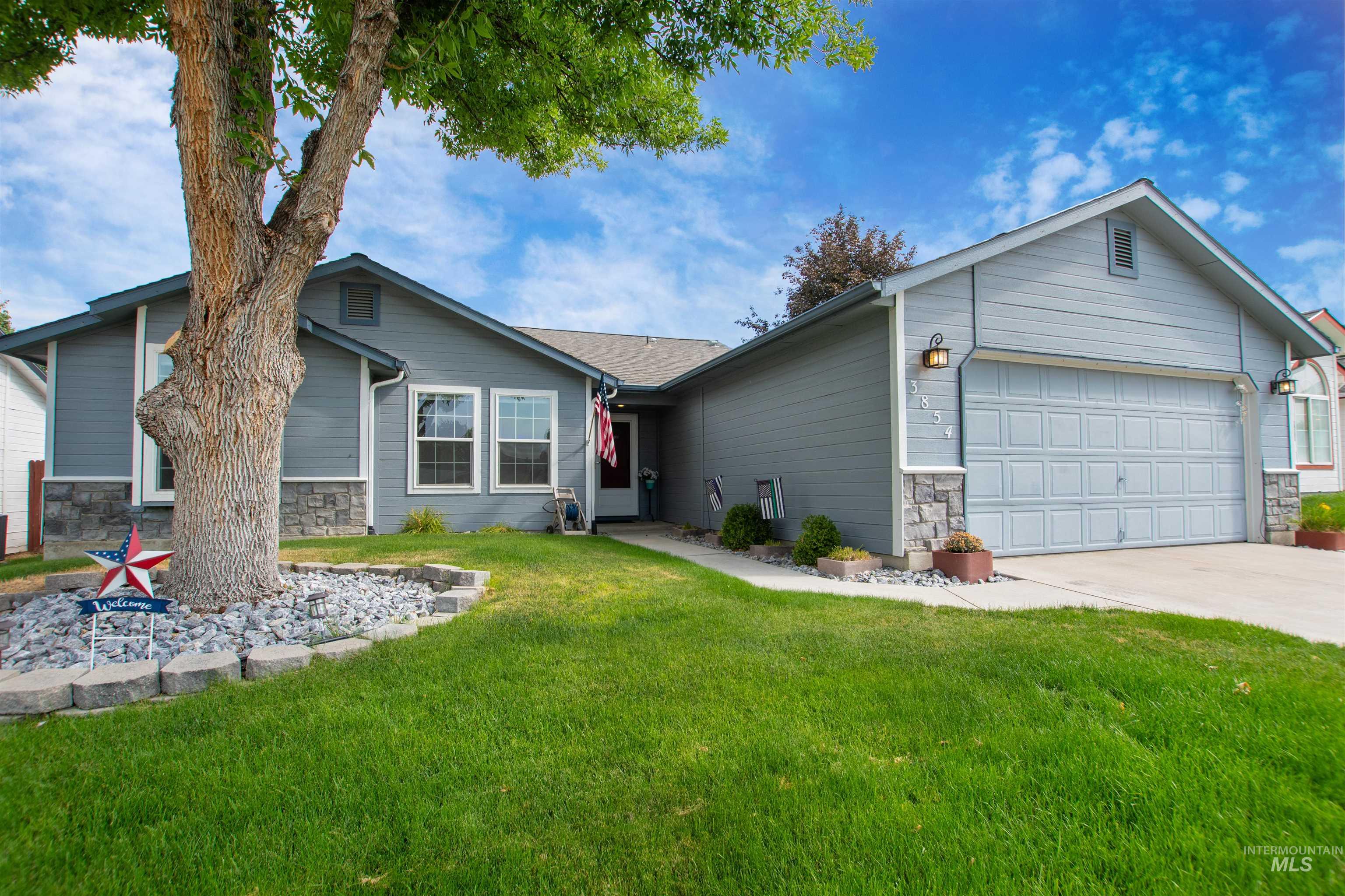 Single story home with stone siding, a garage, a front yard, and driveway