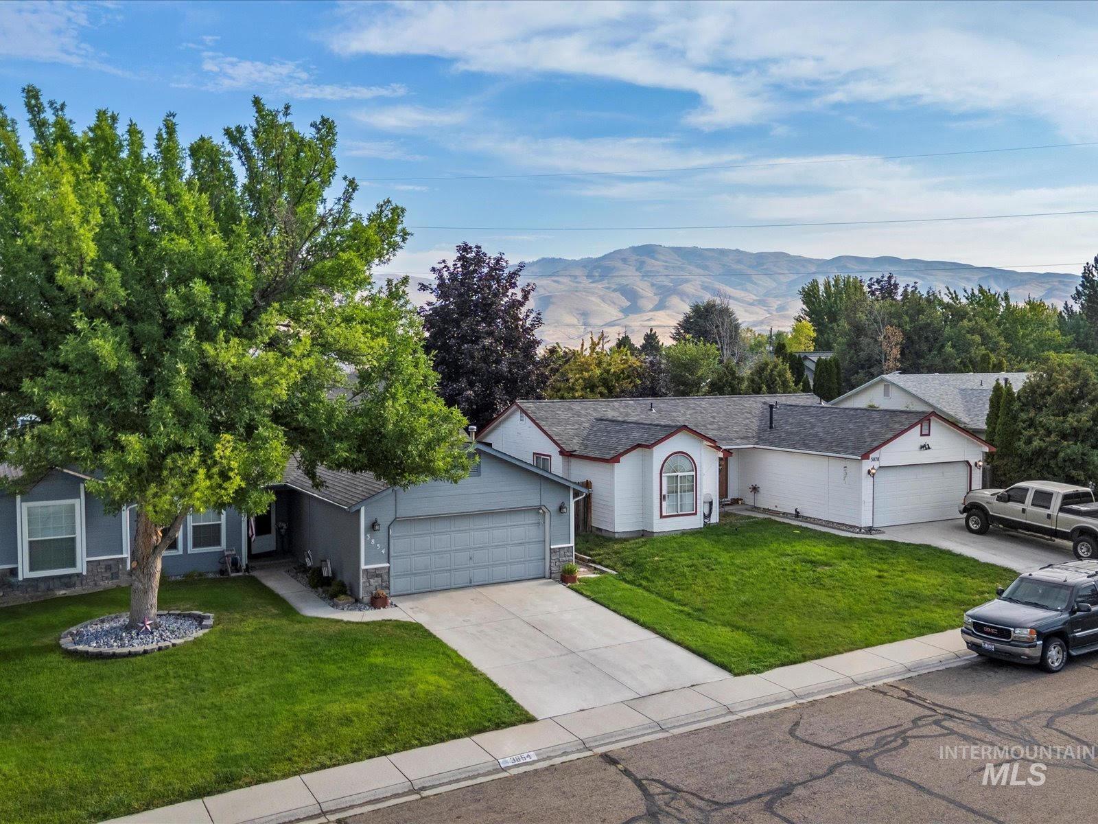 Ranch-style house with a mountain view, a front yard, driveway, an attached garage, and stone siding