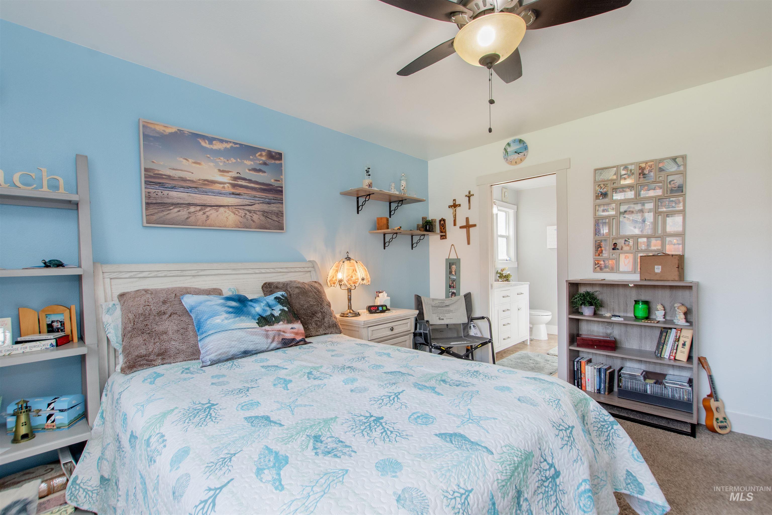 Bedroom with light carpet, ensuite bathroom, and ceiling fan