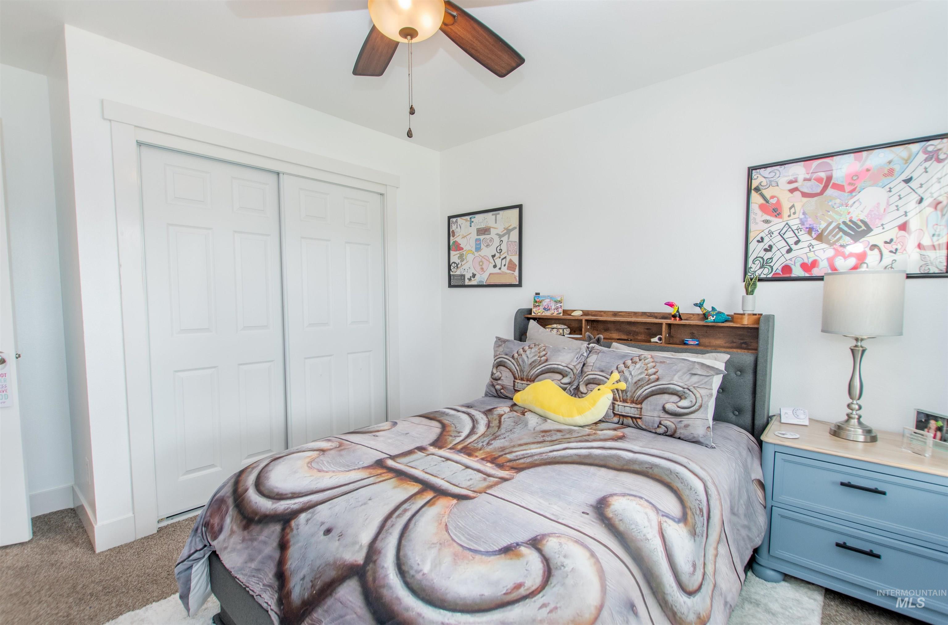 Bedroom featuring light colored carpet, a closet, and a ceiling fan