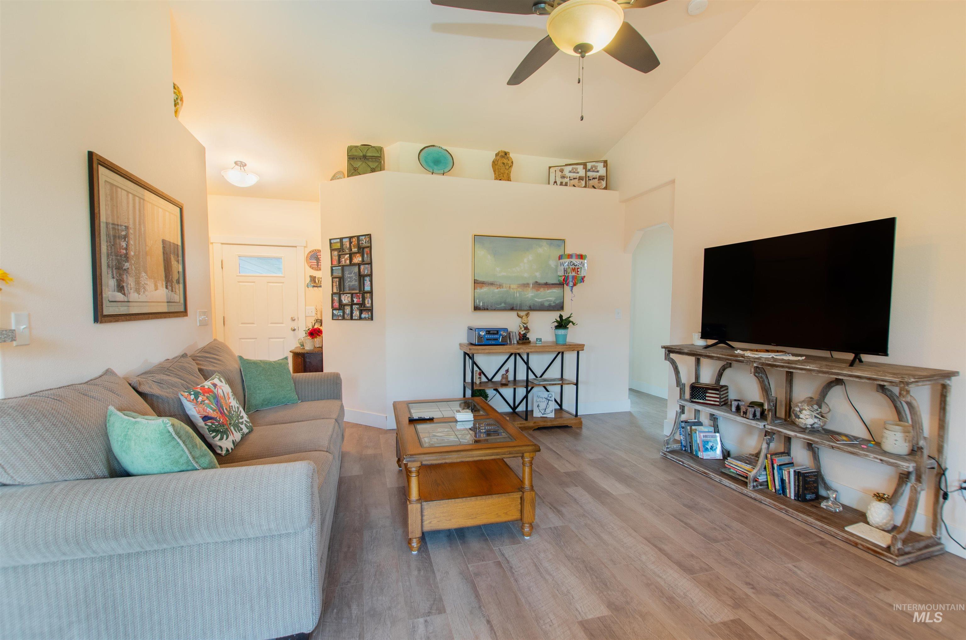 Living room featuring wood finished floors, a ceiling fan, and high vaulted ceiling
