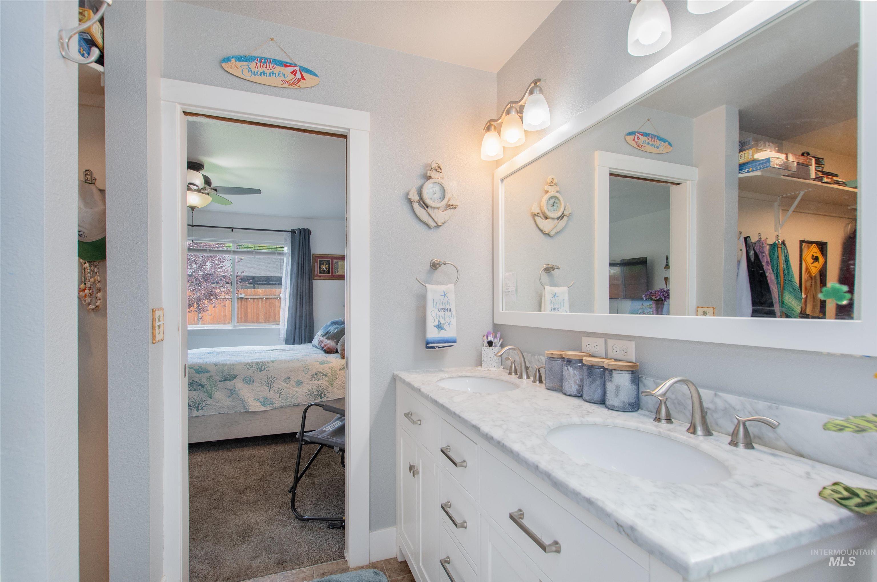 Ensuite bathroom with double vanity and a ceiling fan