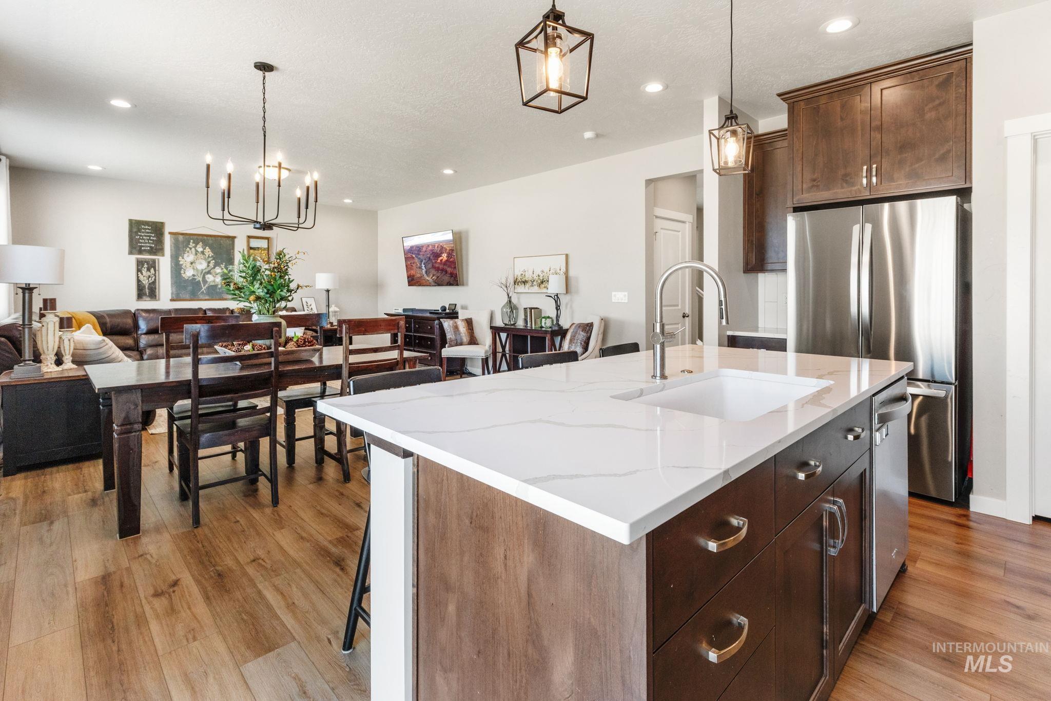 Kitchen with freestanding refrigerator, open floor plan, light wood finished floors, pendant lighting, and recessed lighting