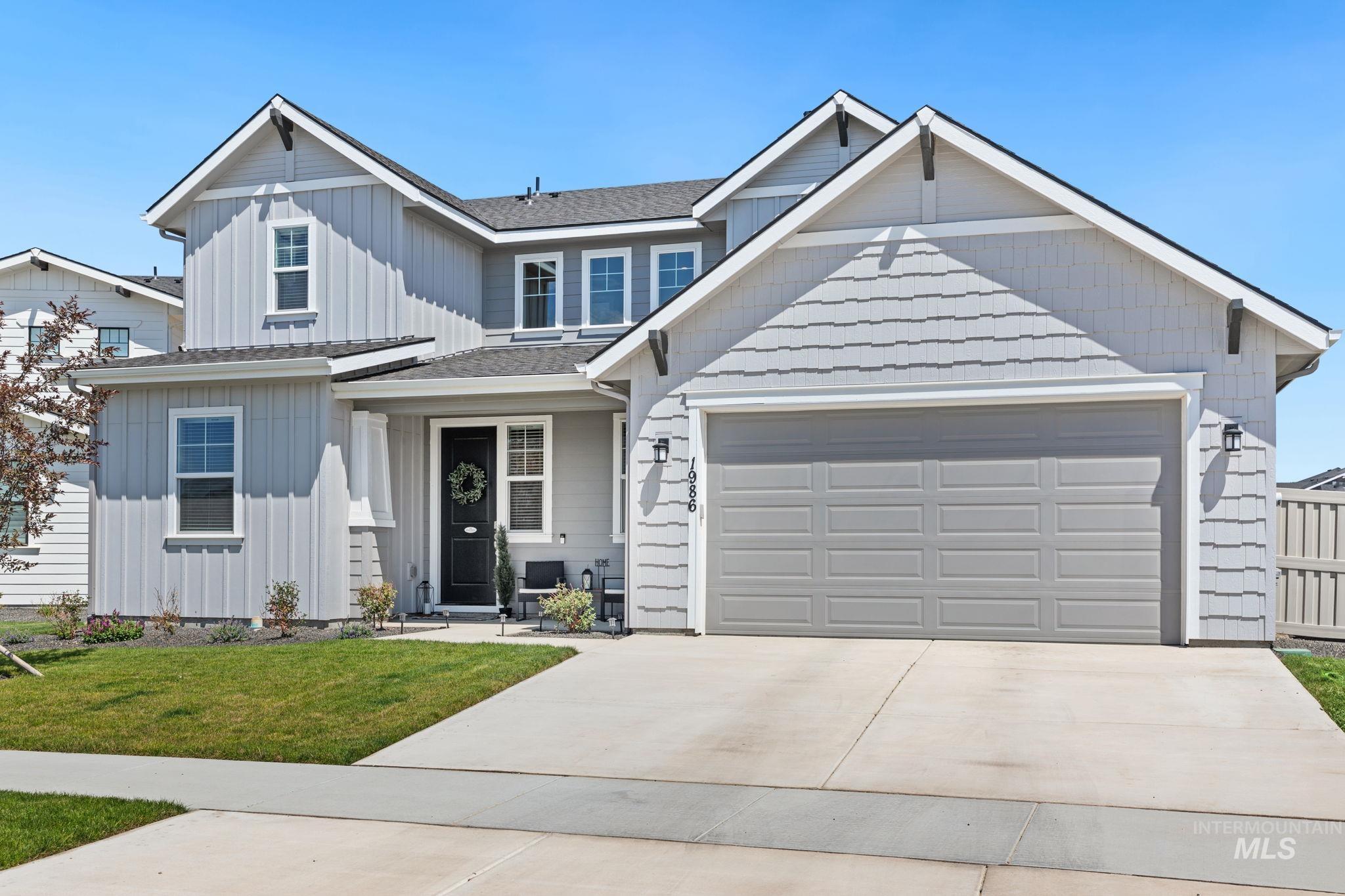 View of front of house with board and batten siding, driveway, a garage, and a front yard