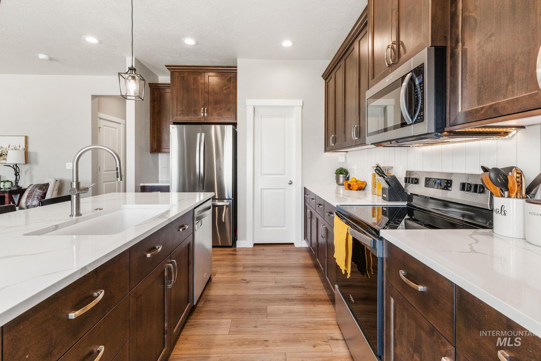 Kitchen featuring stainless steel appliances, light wood finished floors, light stone counters, tasteful backsplash, and recessed lighting