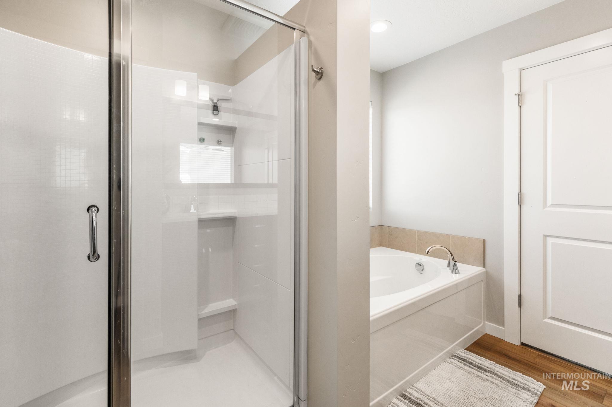 Bathroom featuring a shower stall, a bath, and wood finished floors