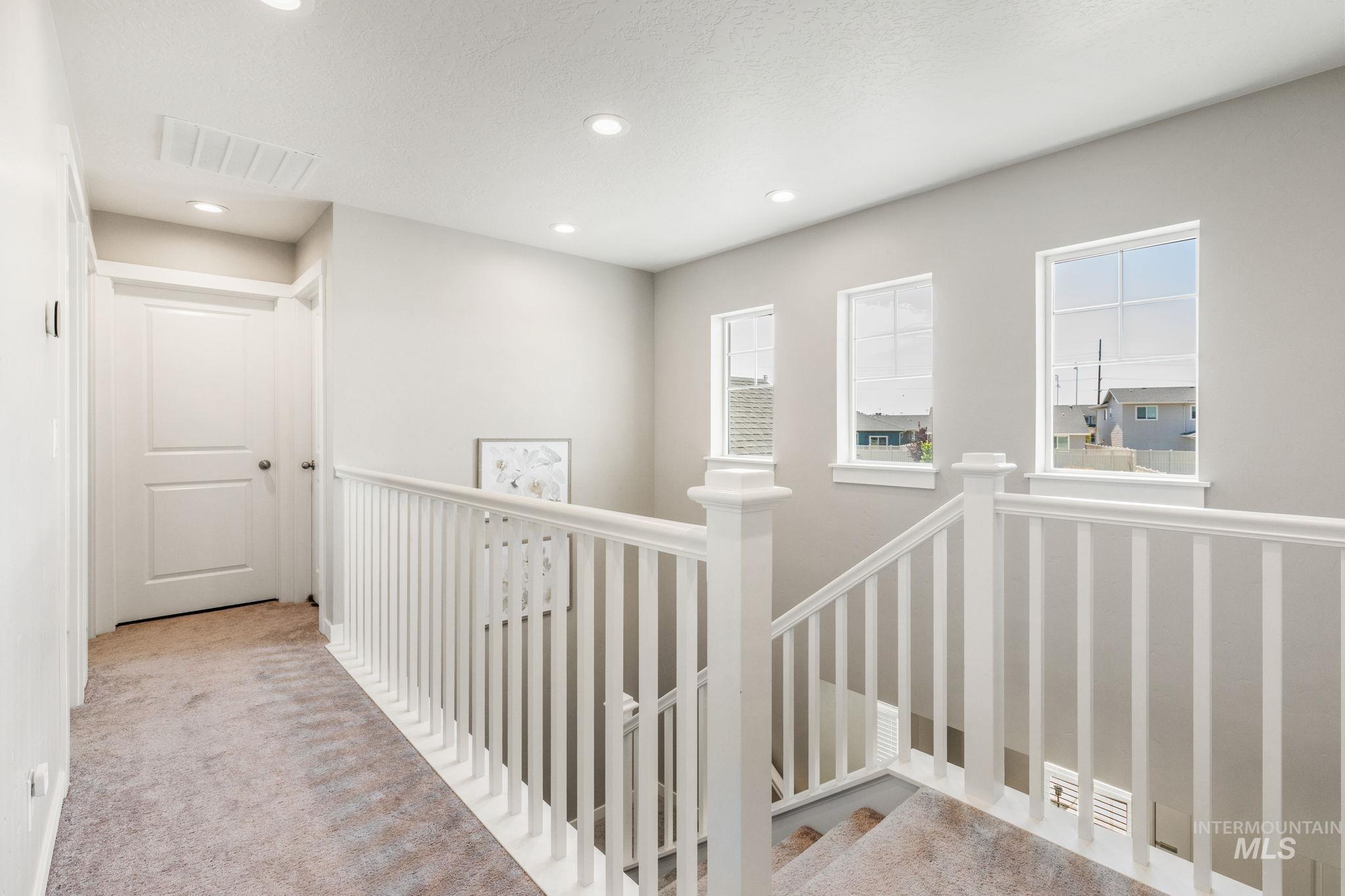 Corridor featuring an upstairs landing, carpet floors, recessed lighting, and a textured ceiling