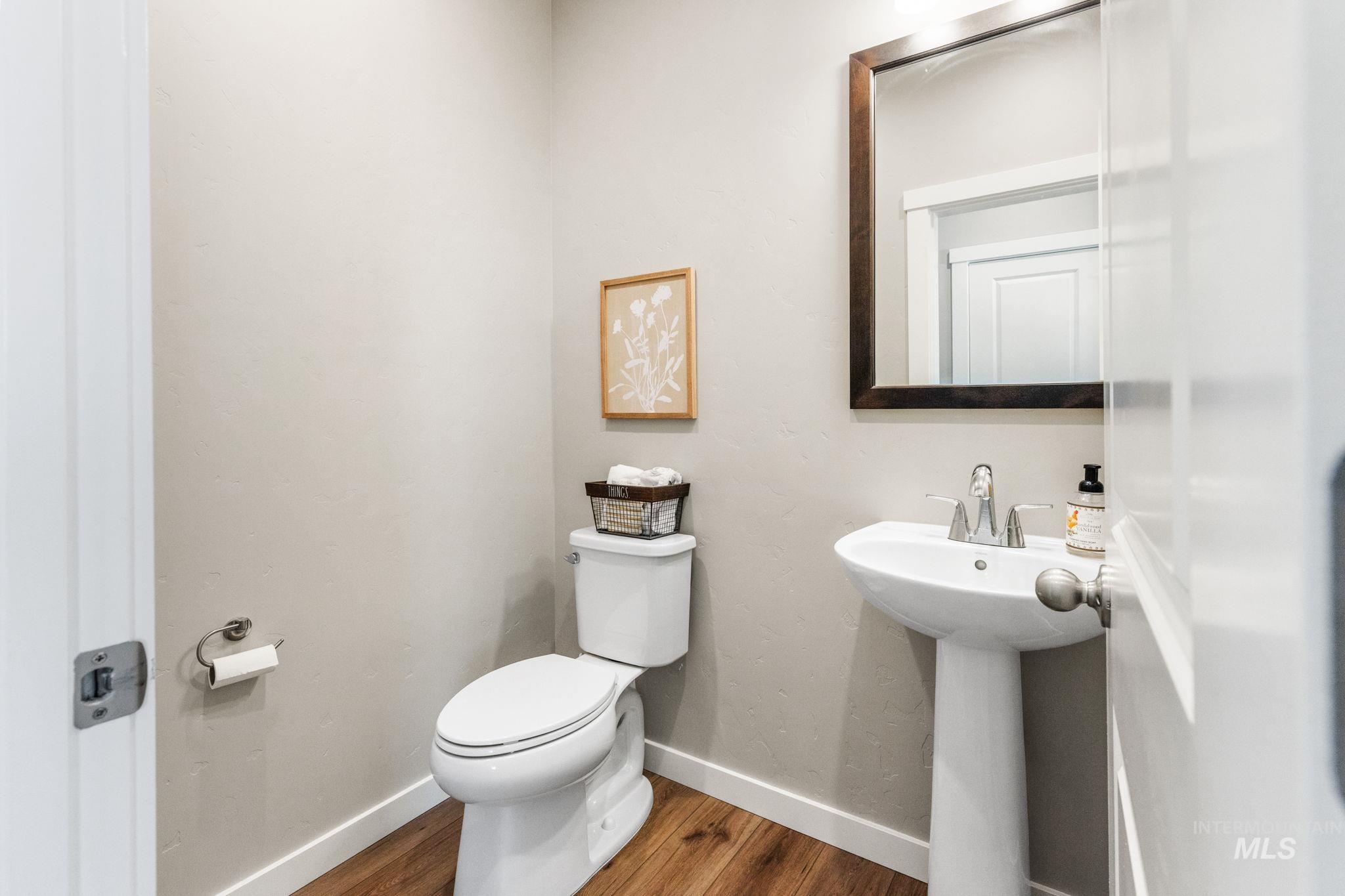 Half bath featuring toilet and wood finished floors
