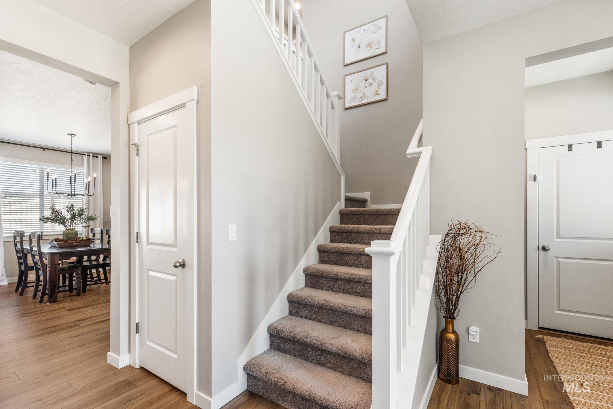 Staircase with a chandelier, wood finished floors, and a textured ceiling