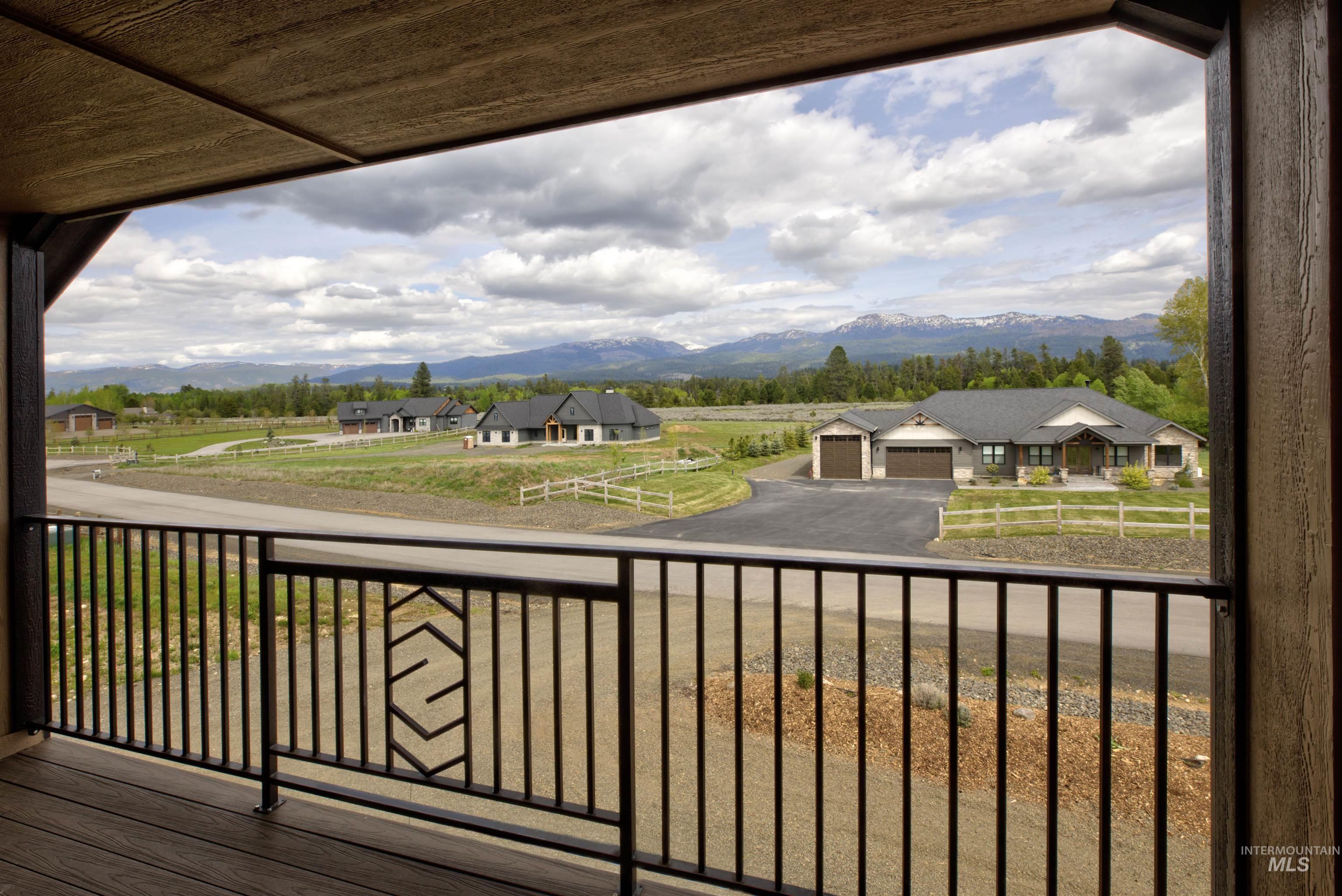 Balcony with composite decking and black metal railing, offering a mountain backdrop and a partial view of a neighboring property with a two-car garage