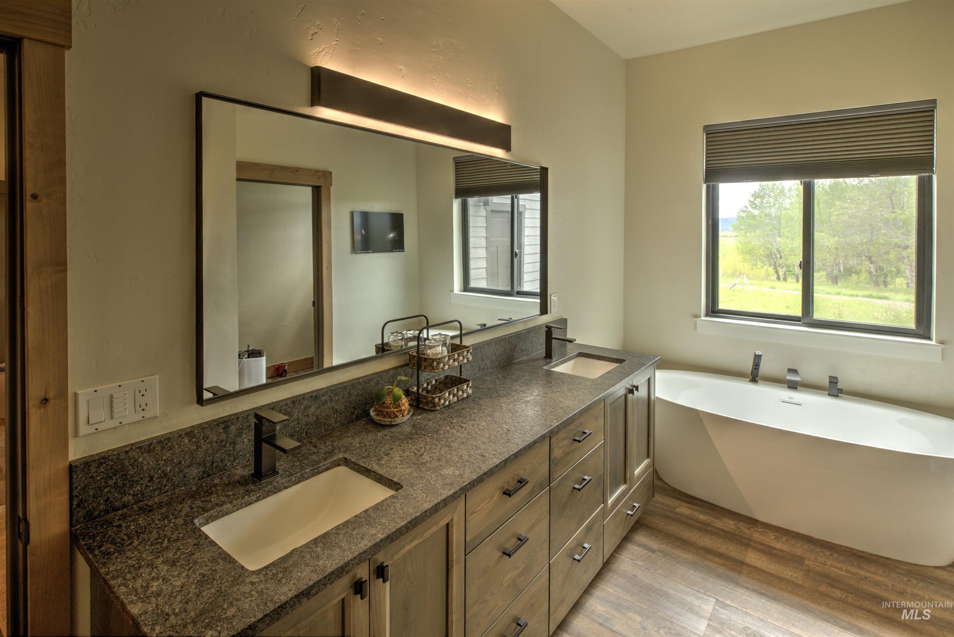 Bathroom featuring an expansive dual vanity with granite-style countertop, undermount sinks, and matte black fixtures
