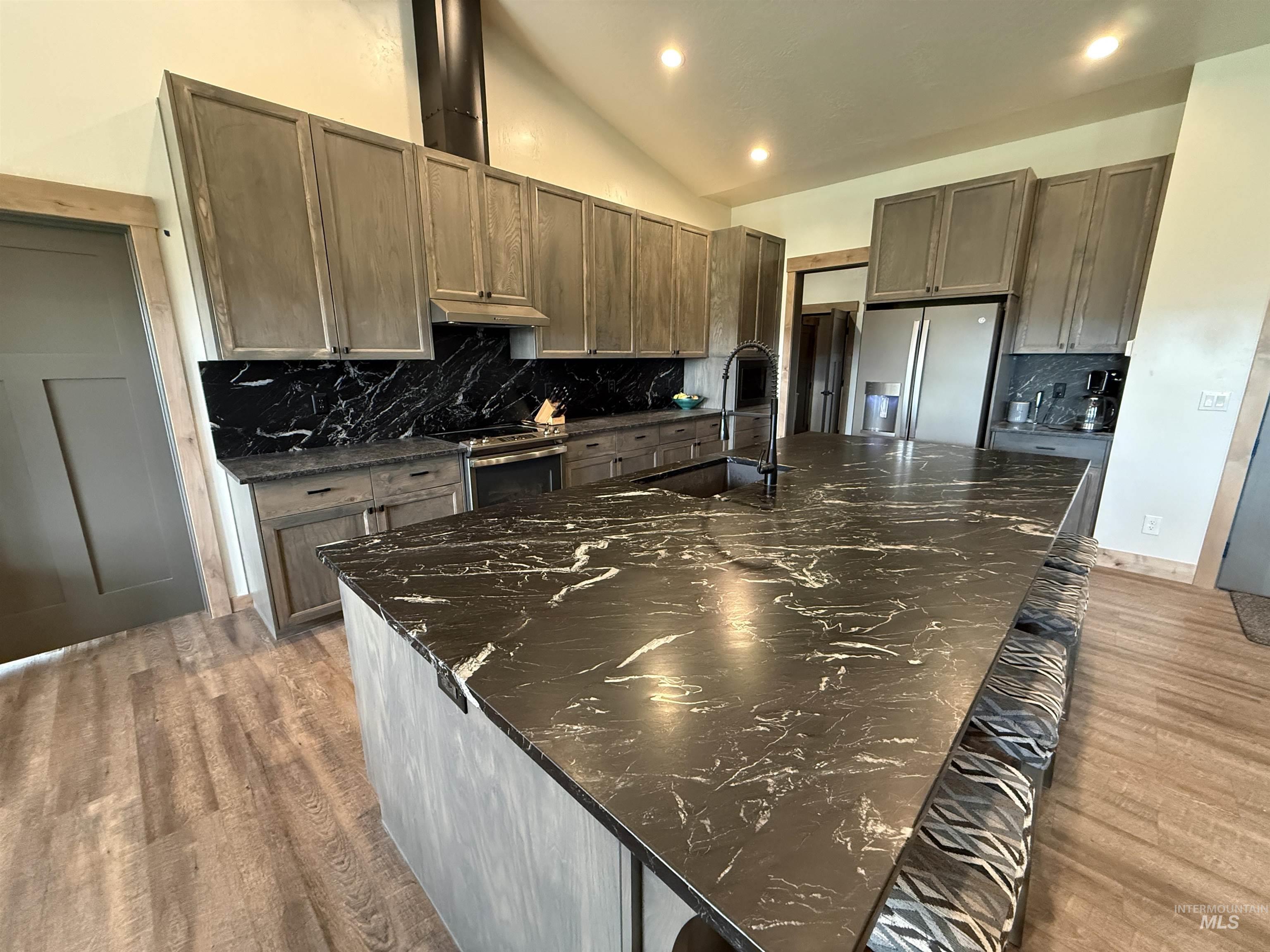 Expansive kitchen island featuring a dark countertop with light veining, complemented by matching perimeter countertops and backsplash