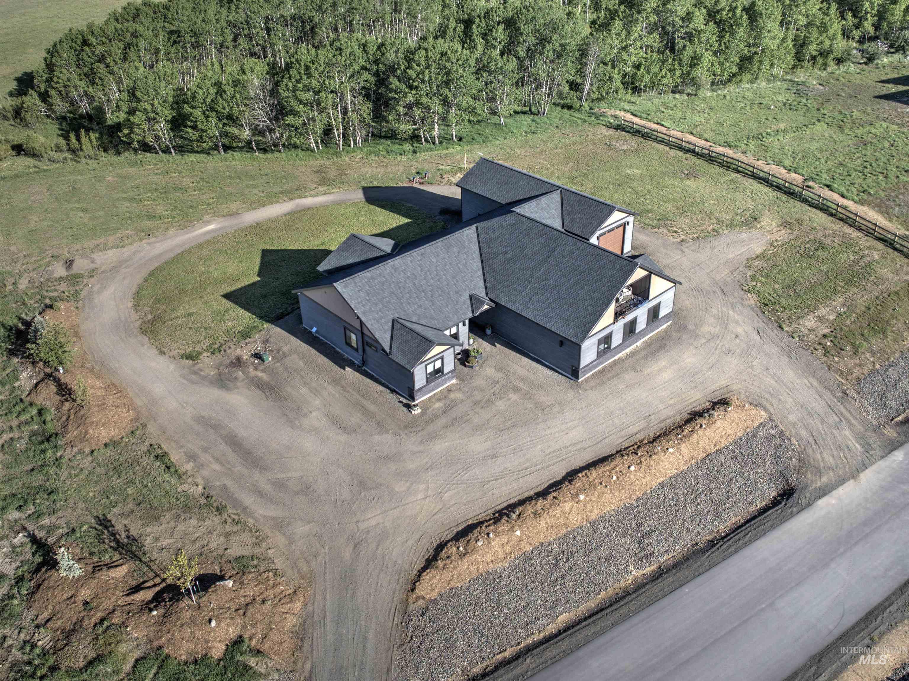 Newly constructed residence featuring a grey exterior with dark shingle roofing